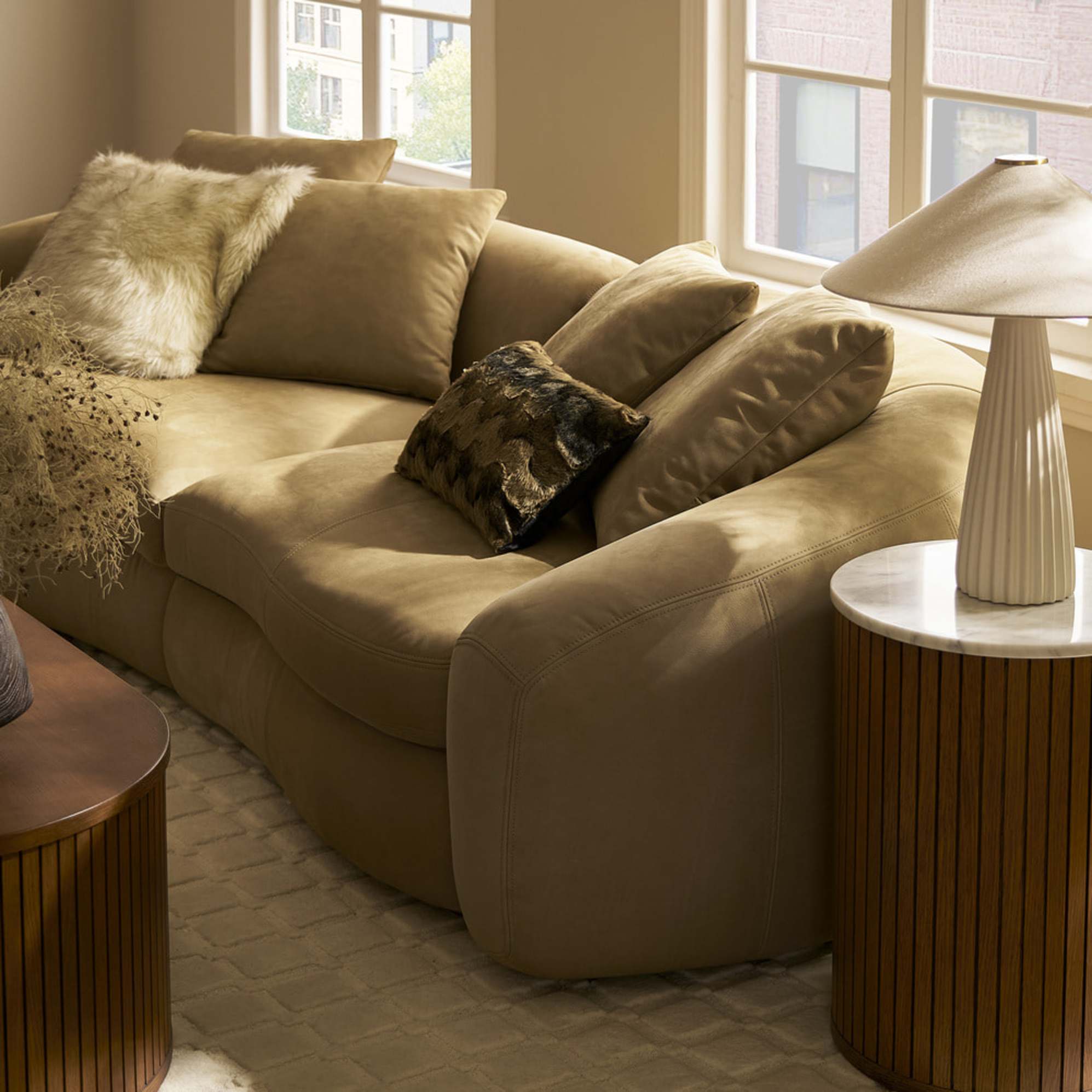 A nubuck leather sofa placed infront of a window.