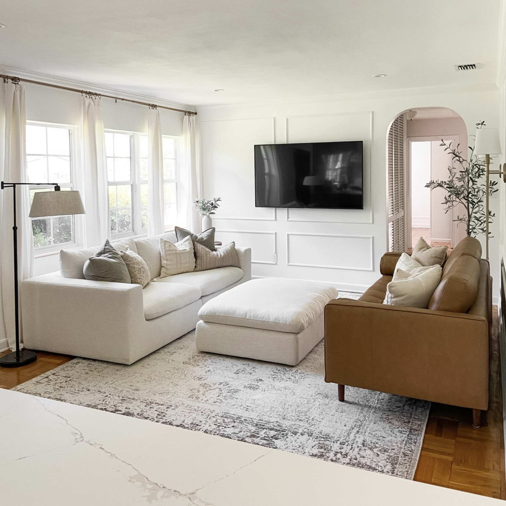 An ottoman placed in the middle of a living room, between a fabric sofa and another leather sofa.