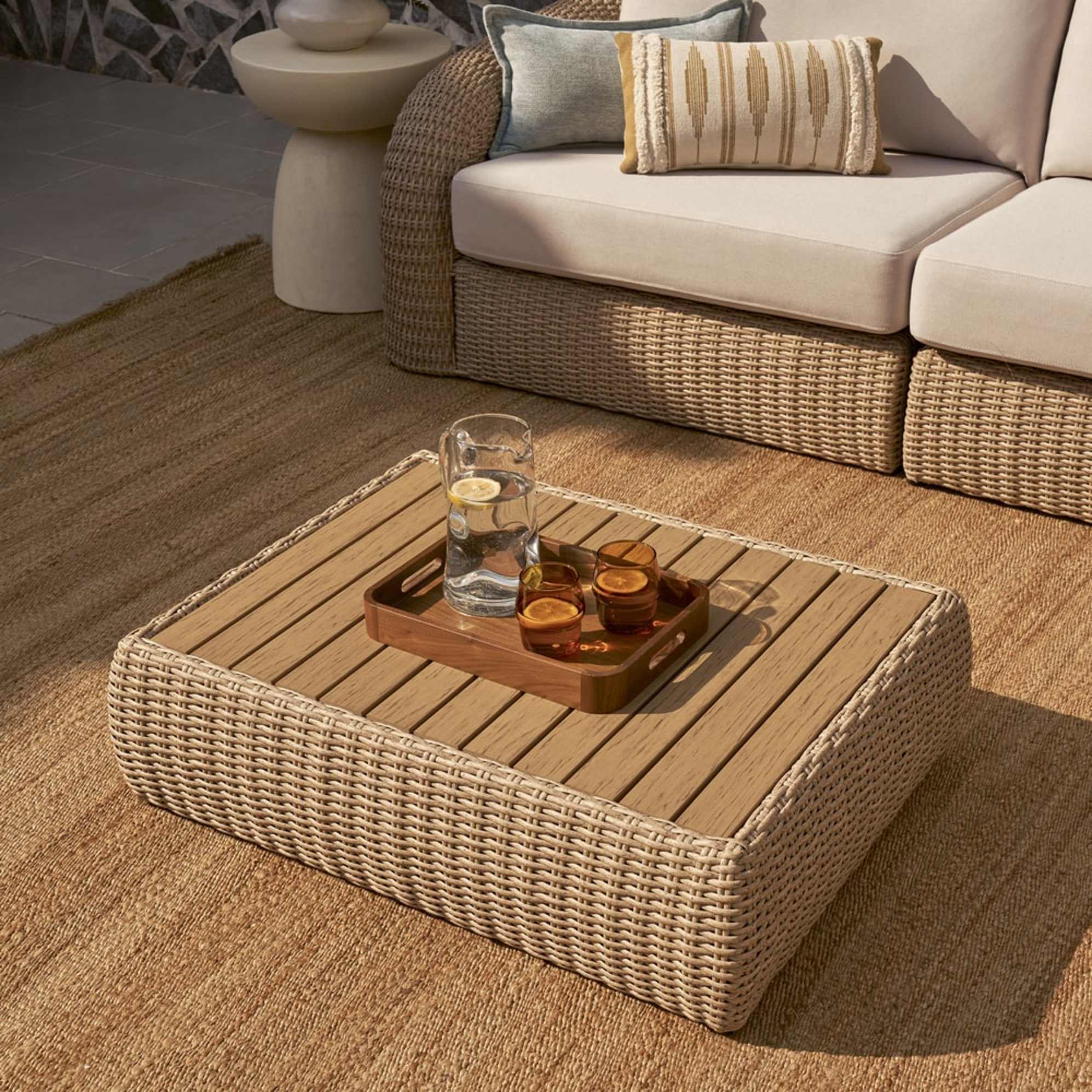 An outdoor ottoman with a tray of drinks.