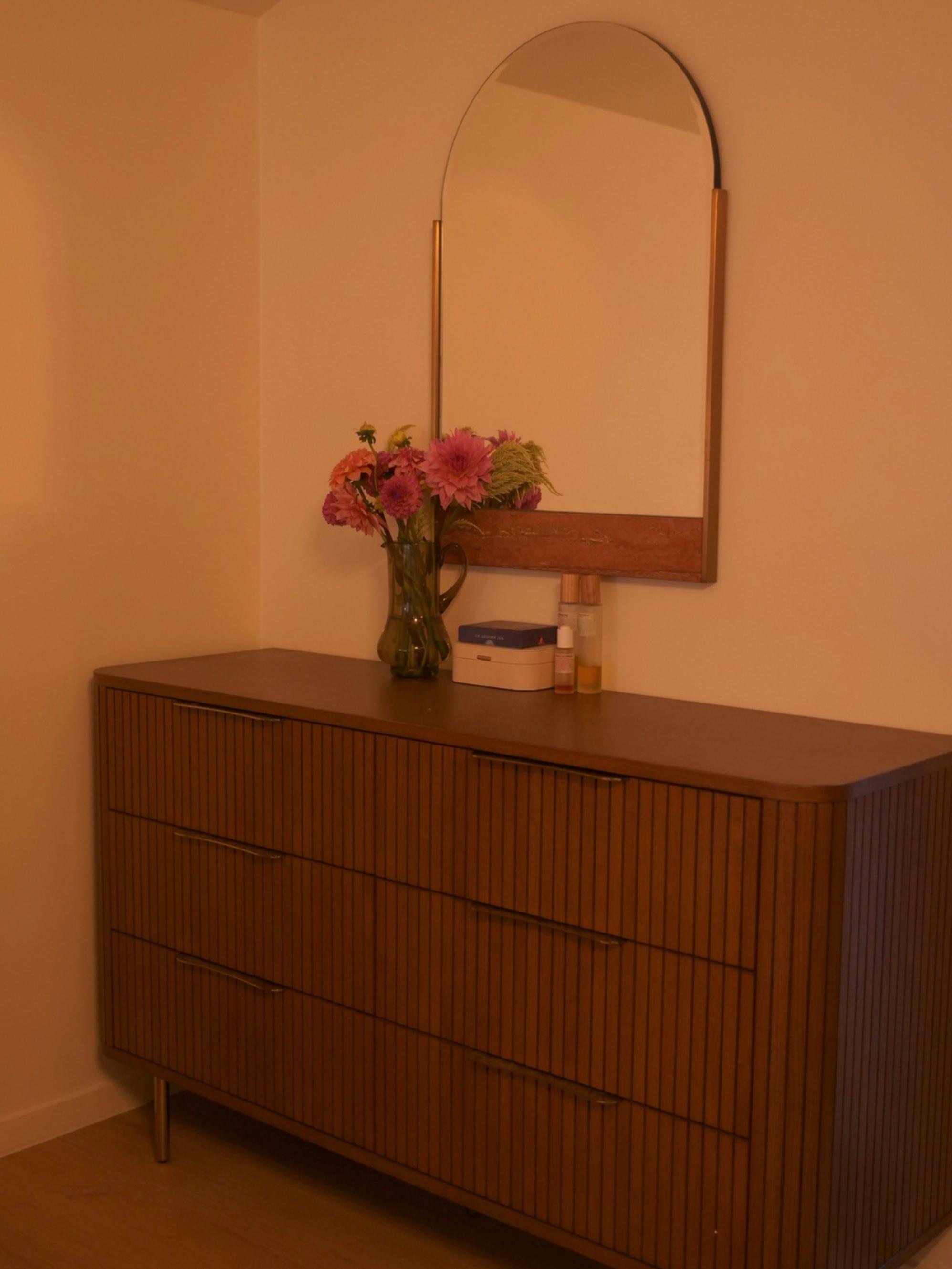 A walnut wood dresser with a mirror placed above it.