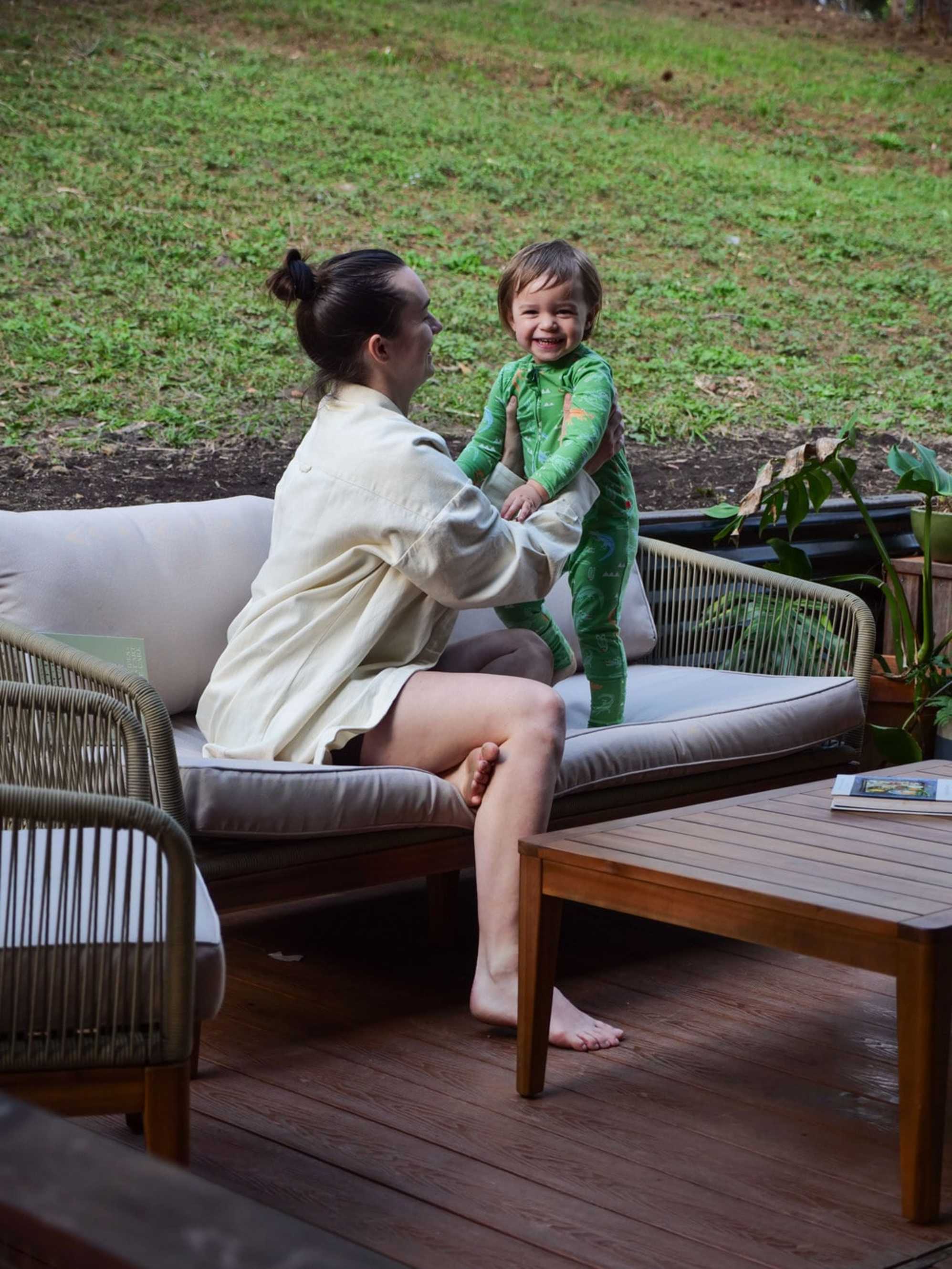 A person holding her toddler while seated on an outdoor sofa.