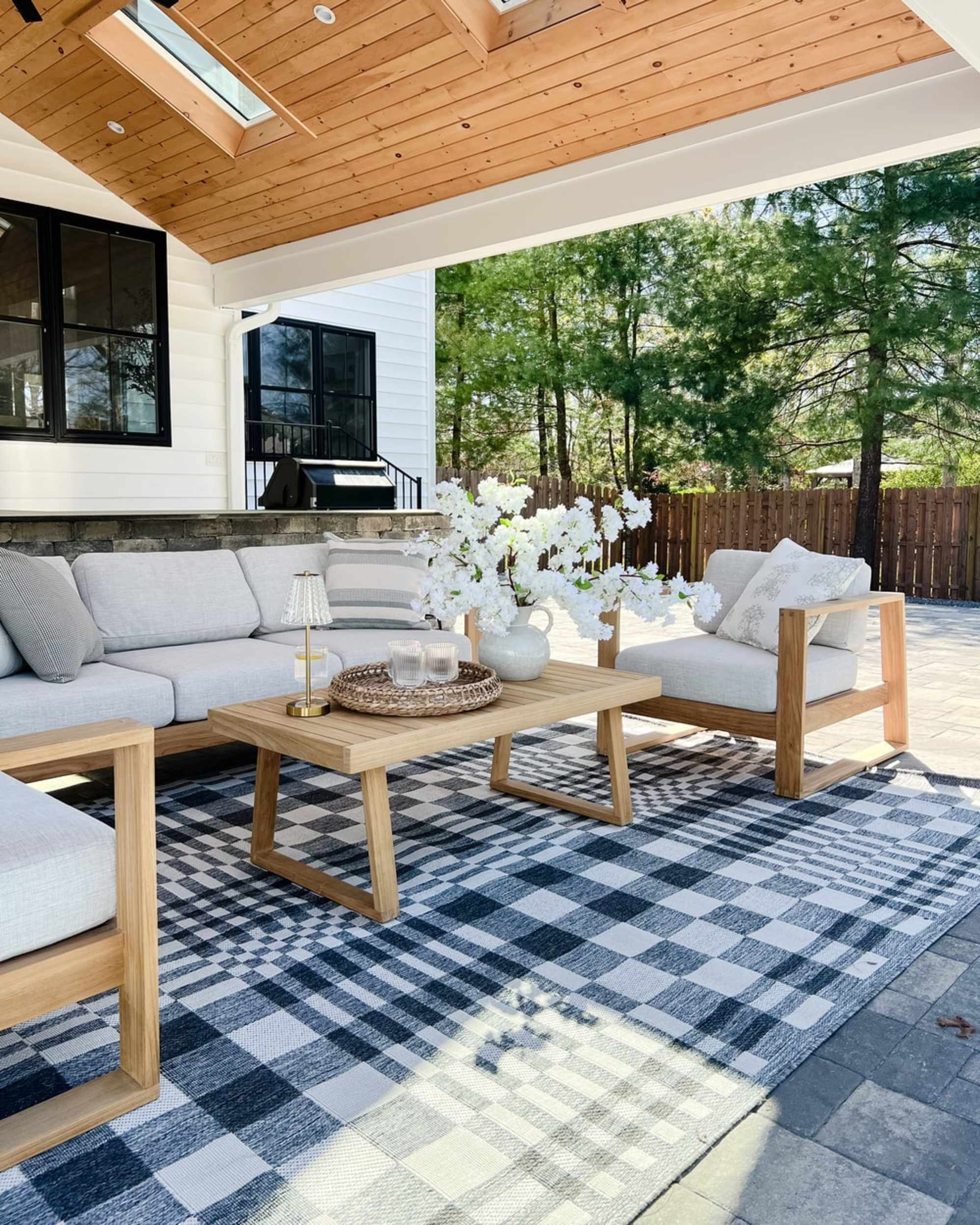 A teak outdoor sofa, armchair, and coffee table placed on a porch.