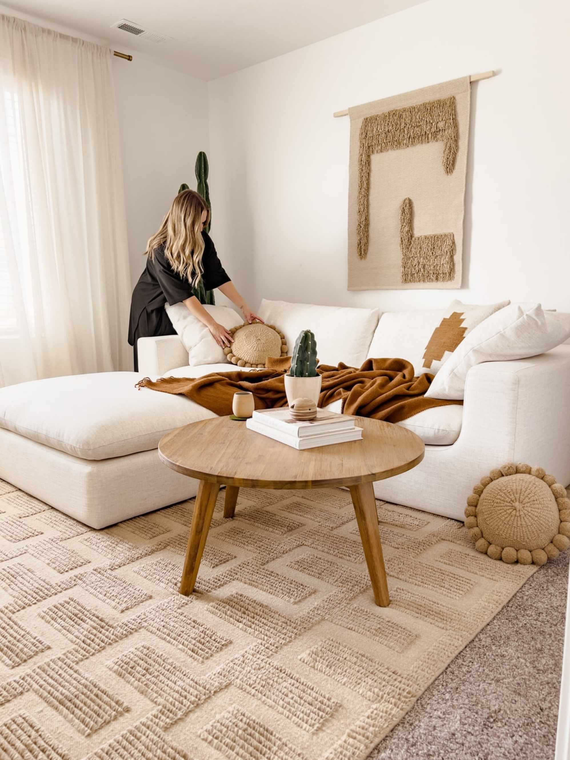 A person arranging pillows on a sofa.