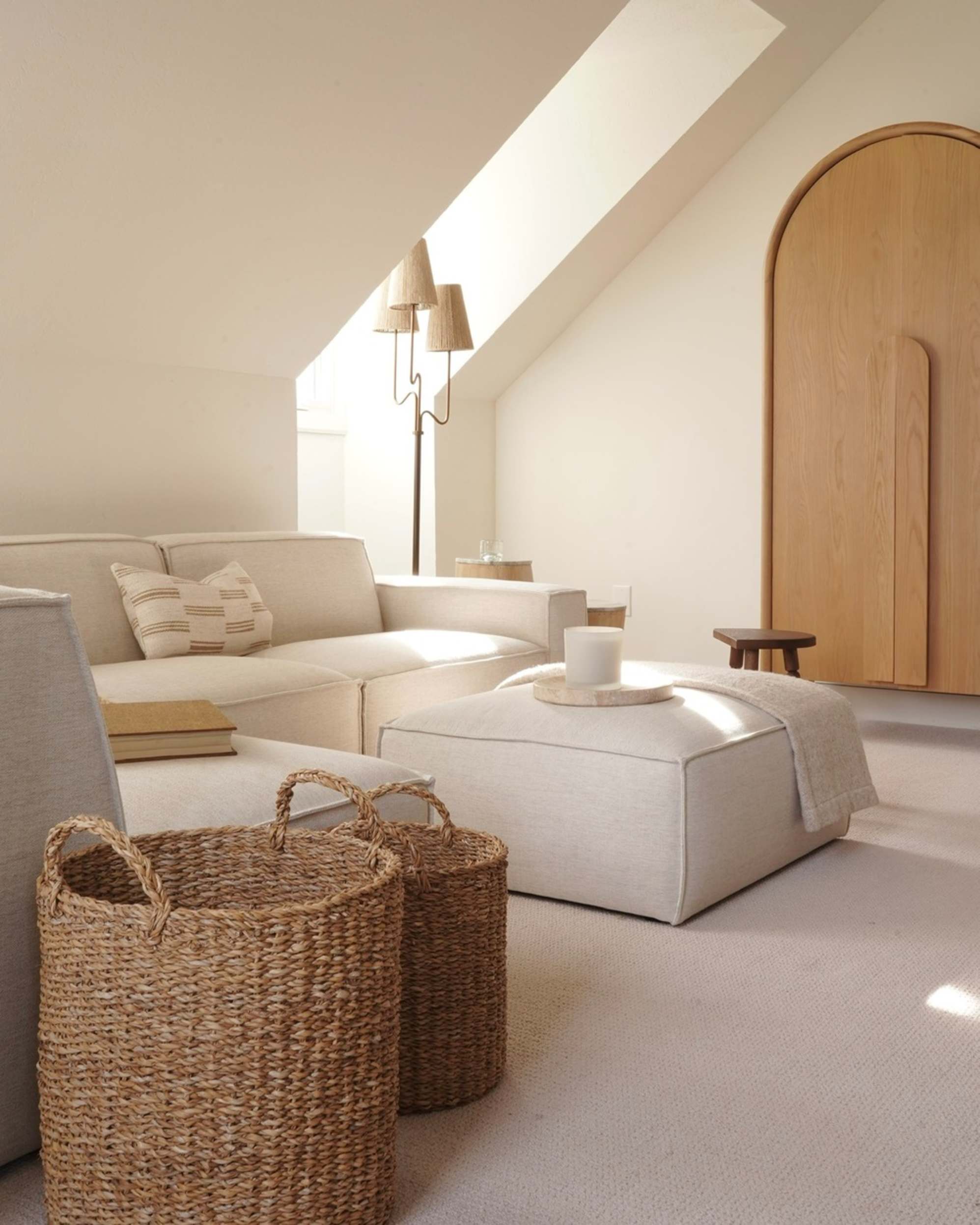A fabric ottoman is placed in the middle of a living room with a tray and candle atop.