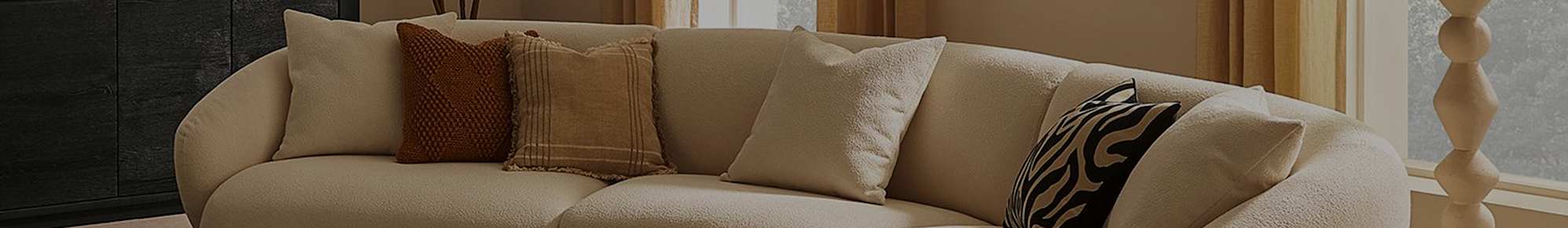 A curved performance fabric sofa with cushions placed atop.