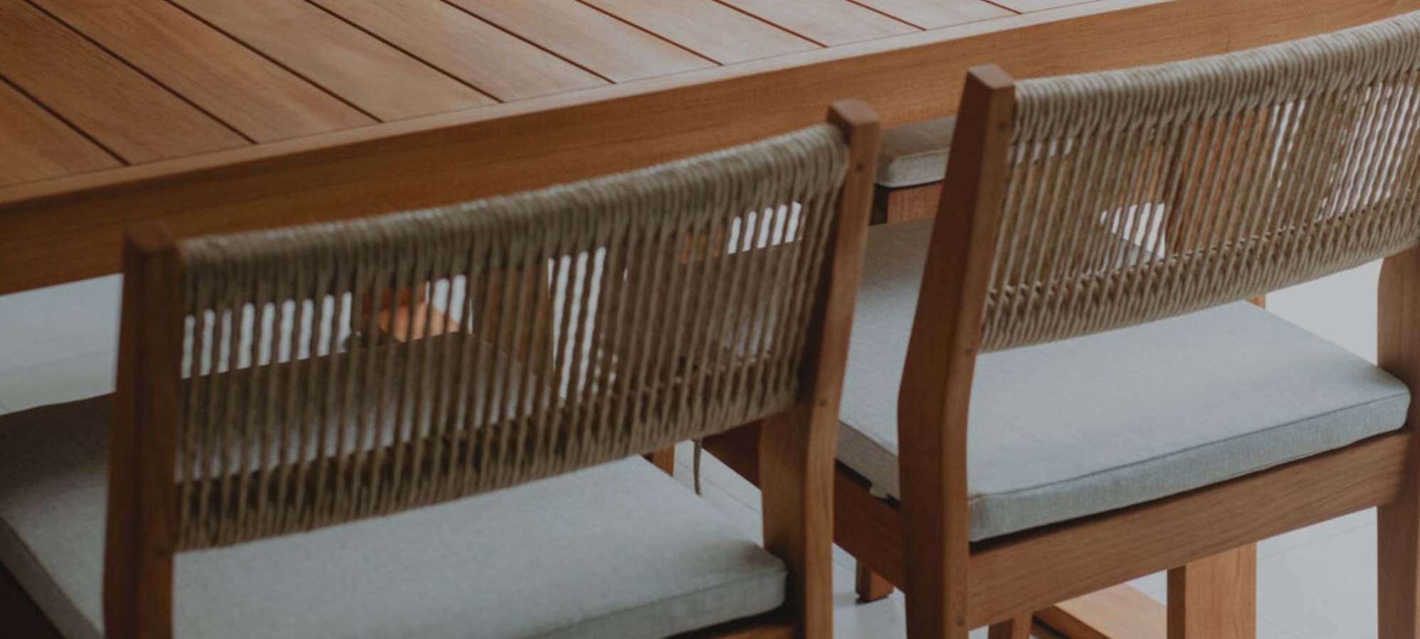 A set of two teak outdoor dining chairs.