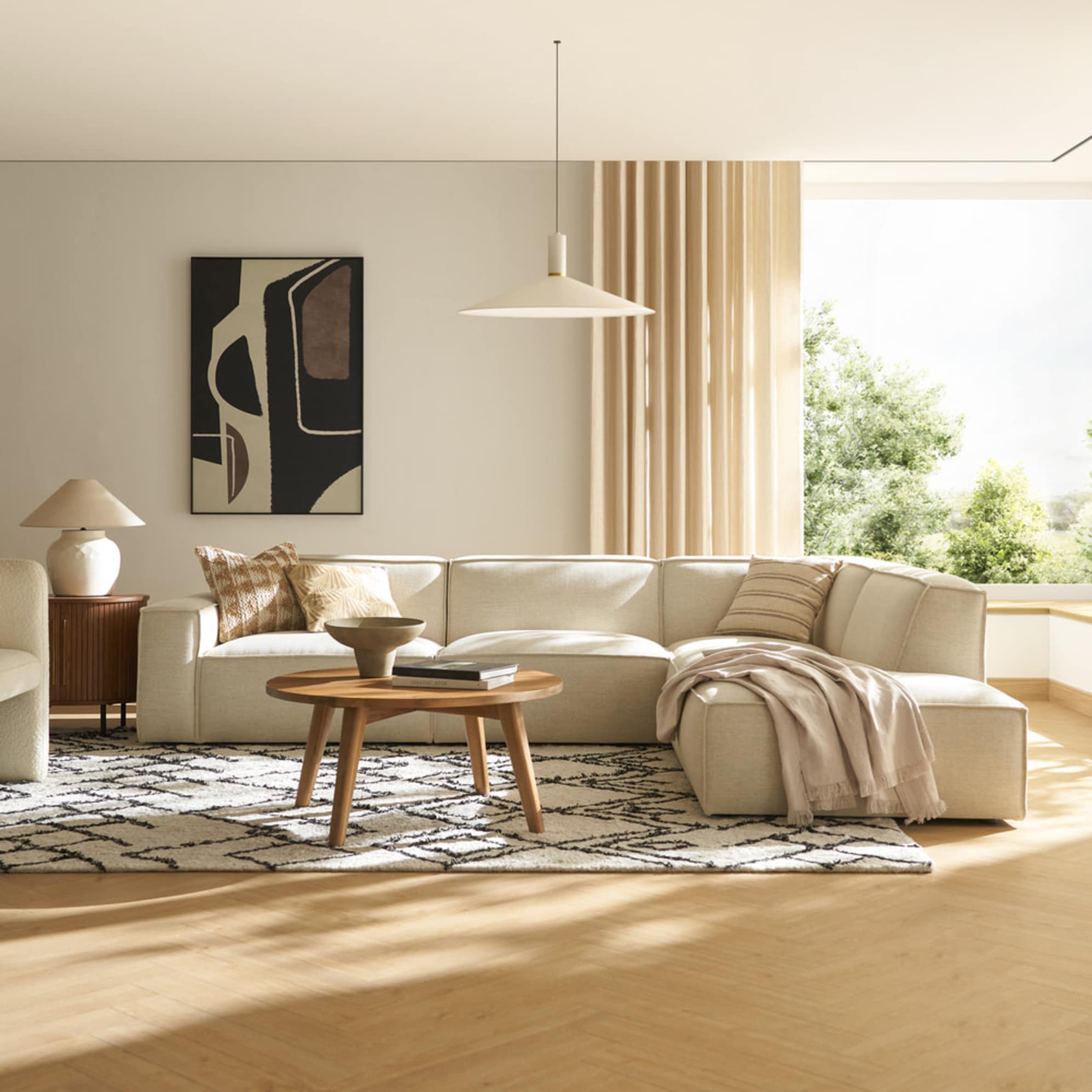 An extended side chaise sectional sofa placed in a living room with a wooden round coffee table and an area rug.