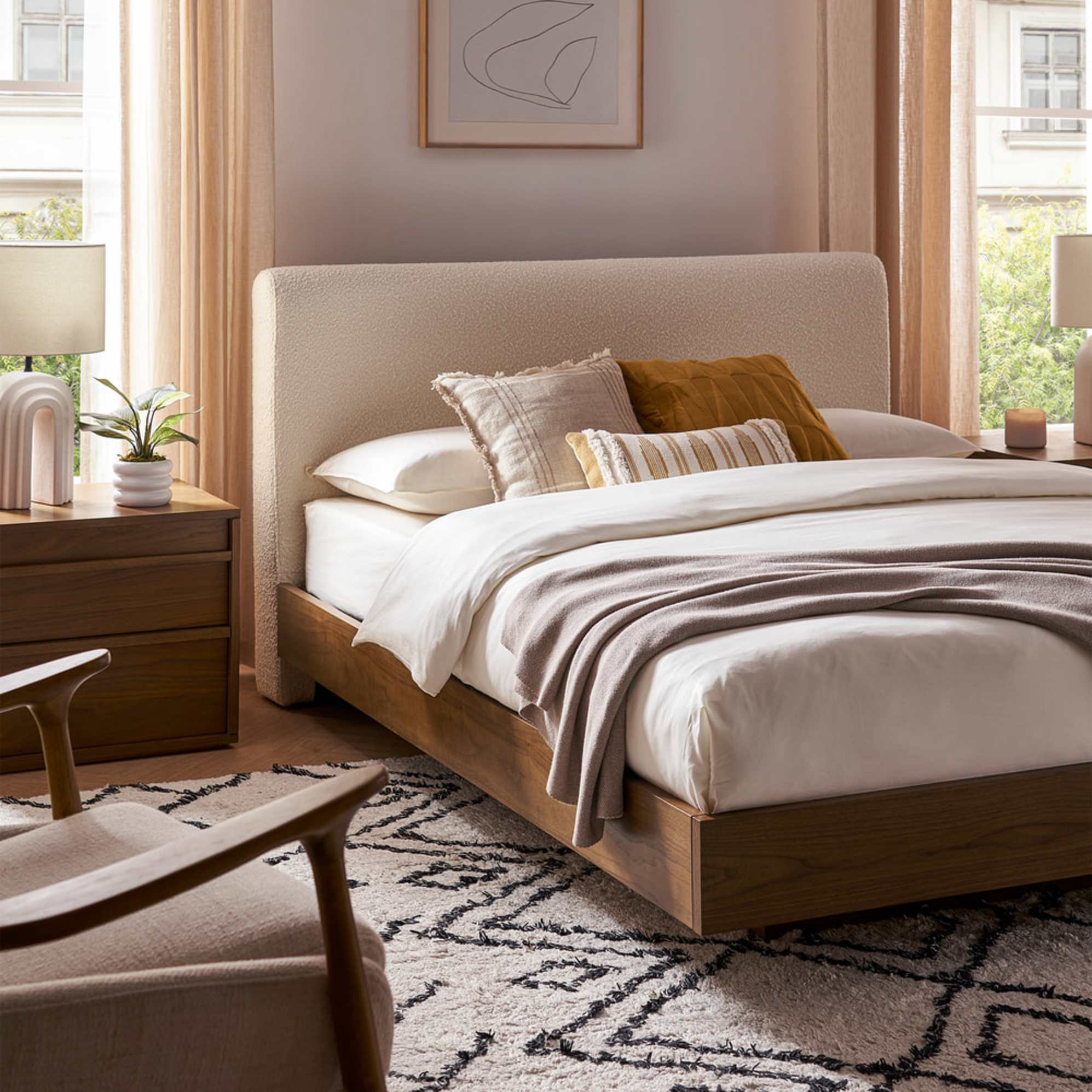 A bed with a bouclé headboard and wooden bed base.