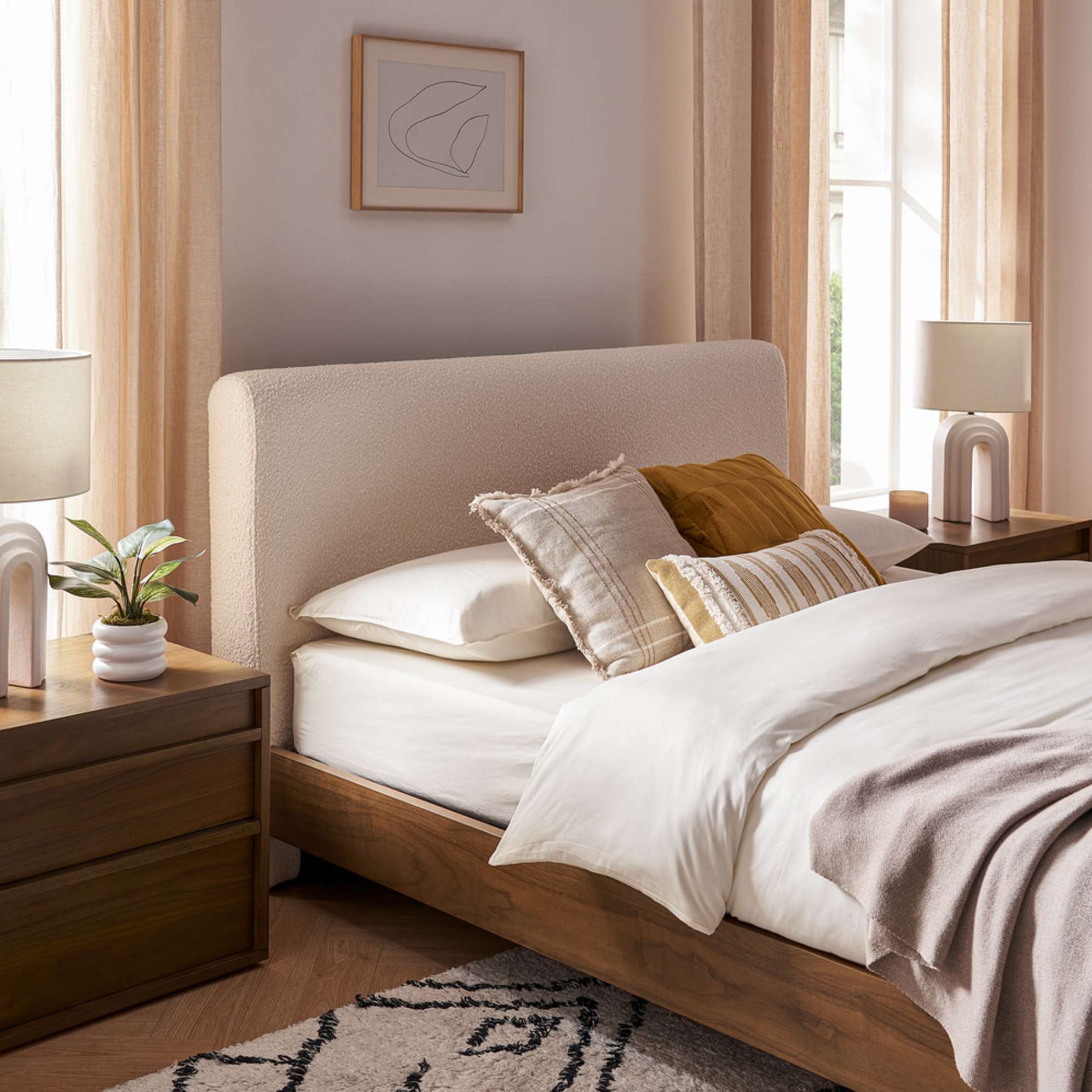 A bouclé bed with two matching wooden nightstands in a bedroom.