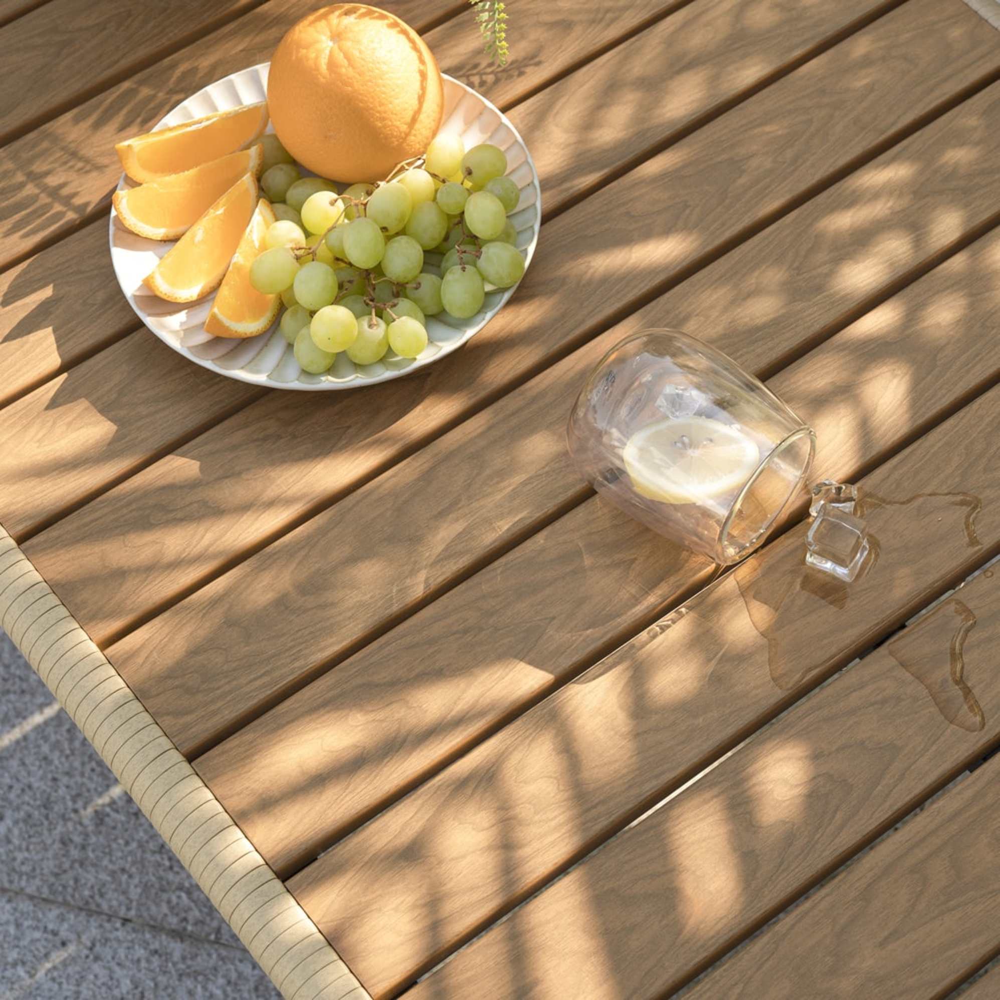 A wooden dining table with a plate of fruits and a cup of water.