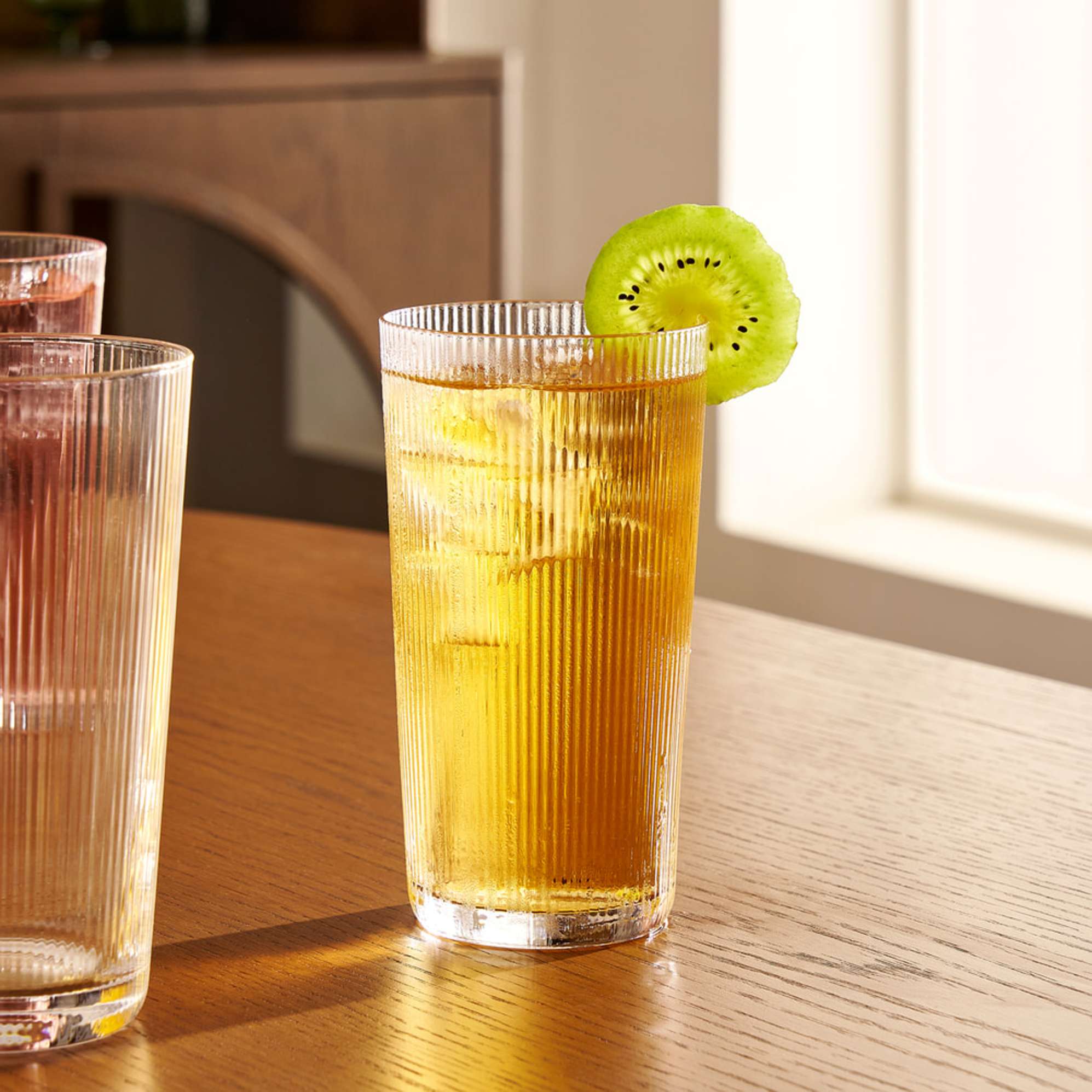 A drinking glasses with fluted detailing filled with a drink.