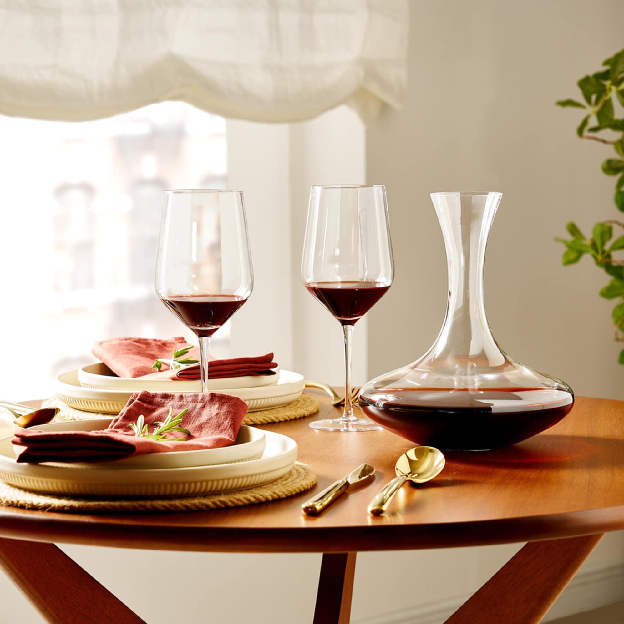 Two red wine glasses and a decanter placed on a dining table.