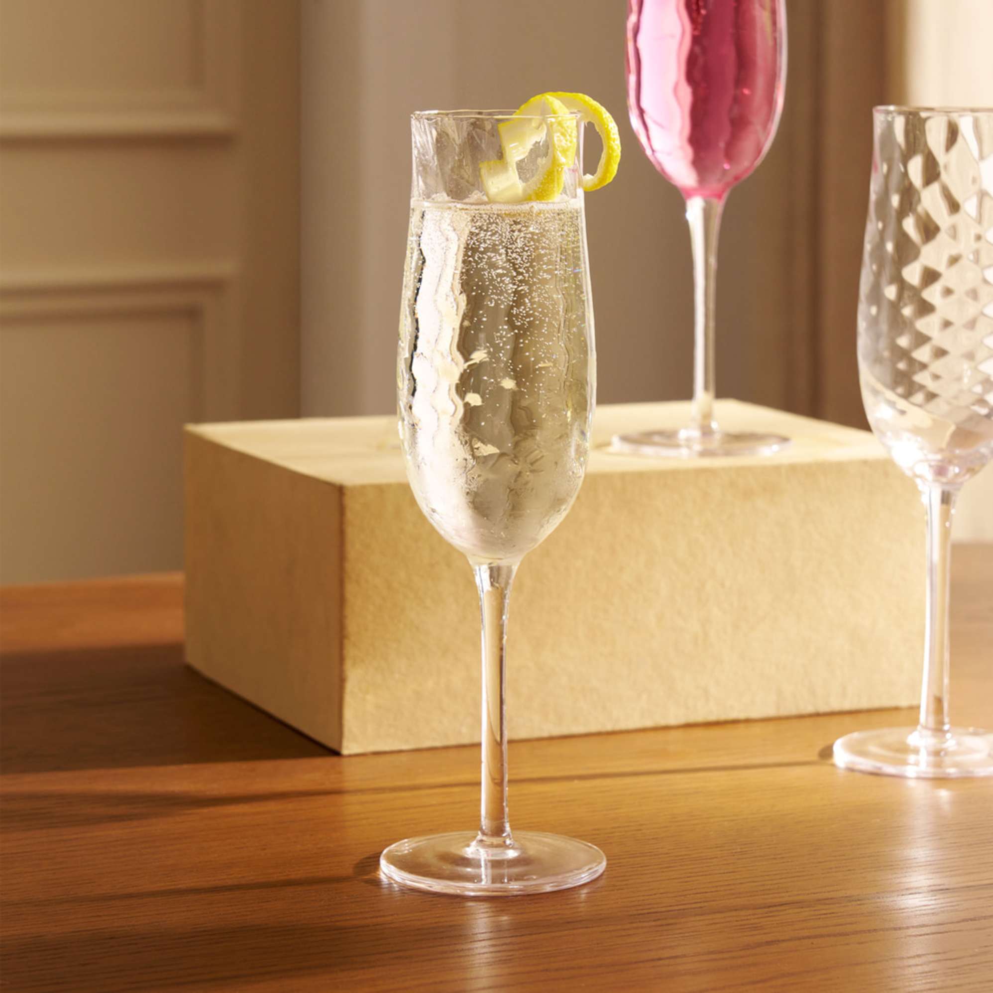 A champagne glass filled with a drink and topped off with lemon zest decoration.