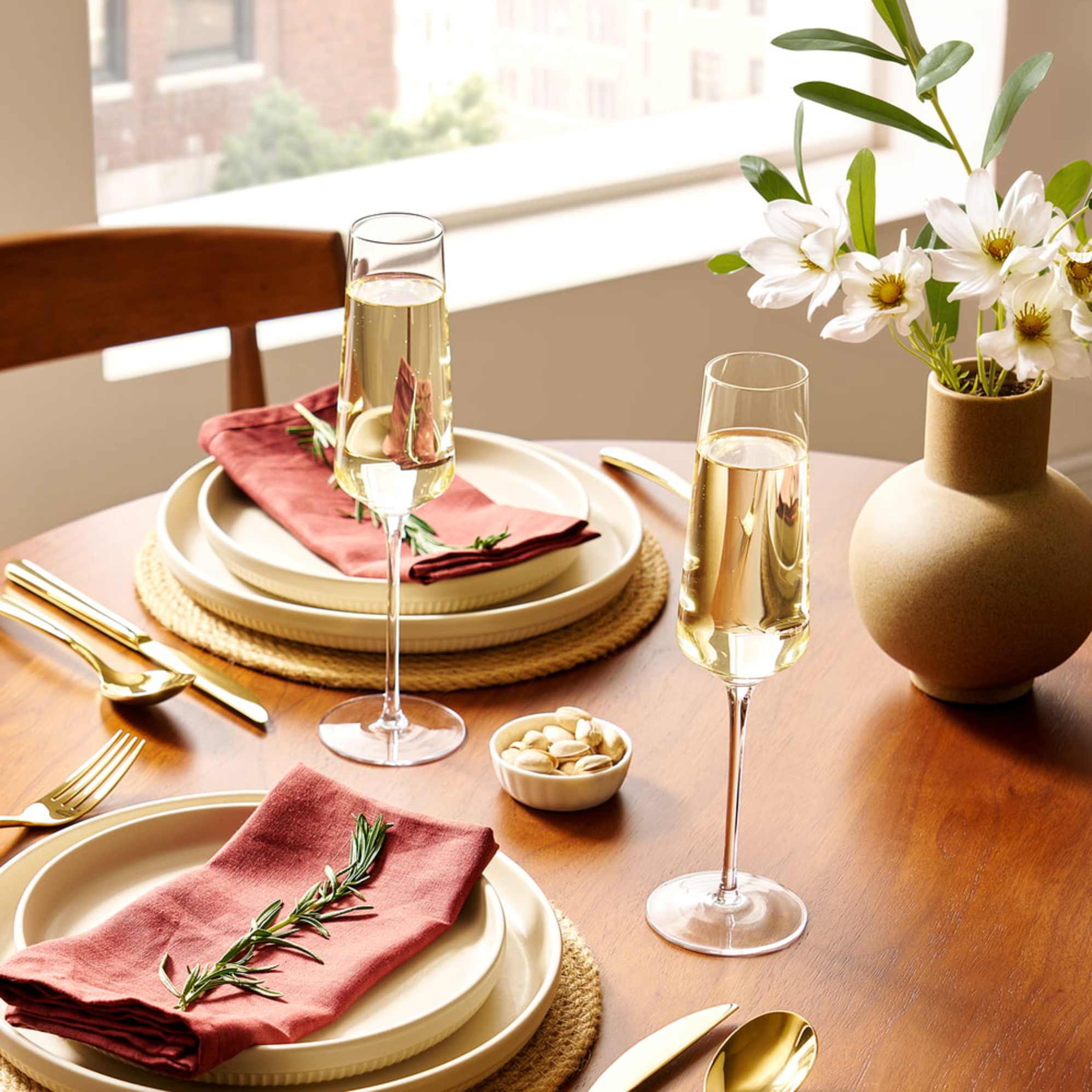 Two champagne glasses filled with drinks are placed on a round dining table with tableware.