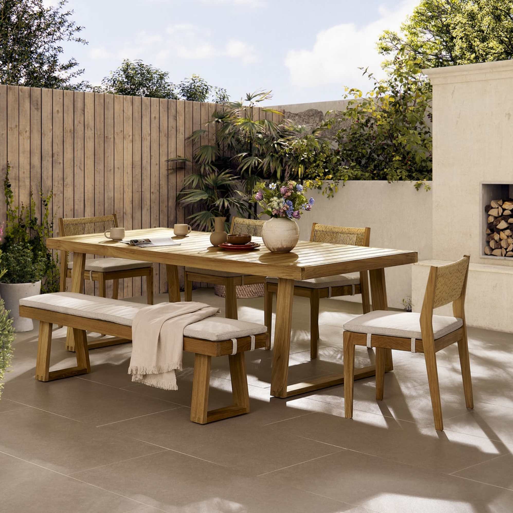 A teak wood dining table with matching dining chairs and a bench.