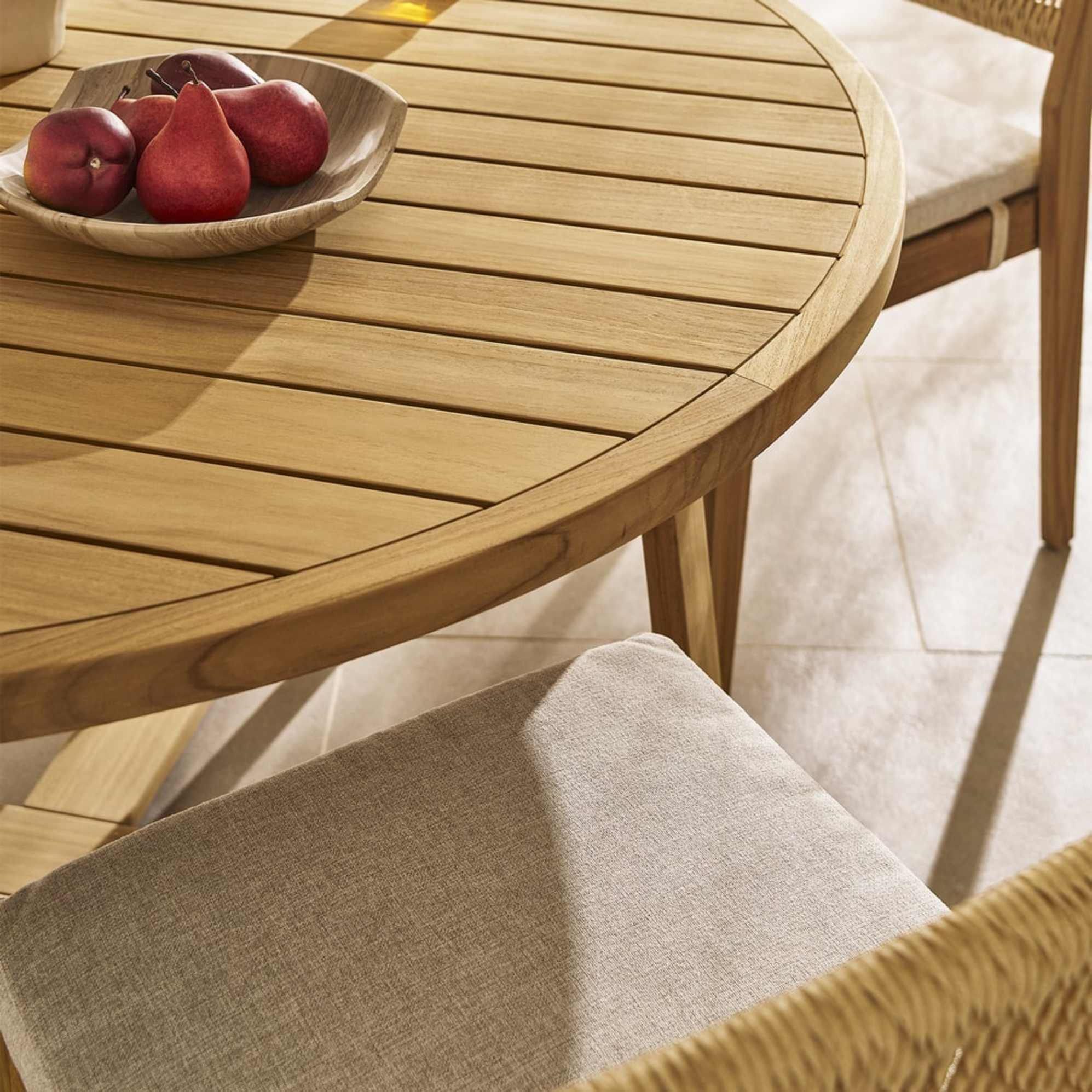 A round teak outdoor dining table.