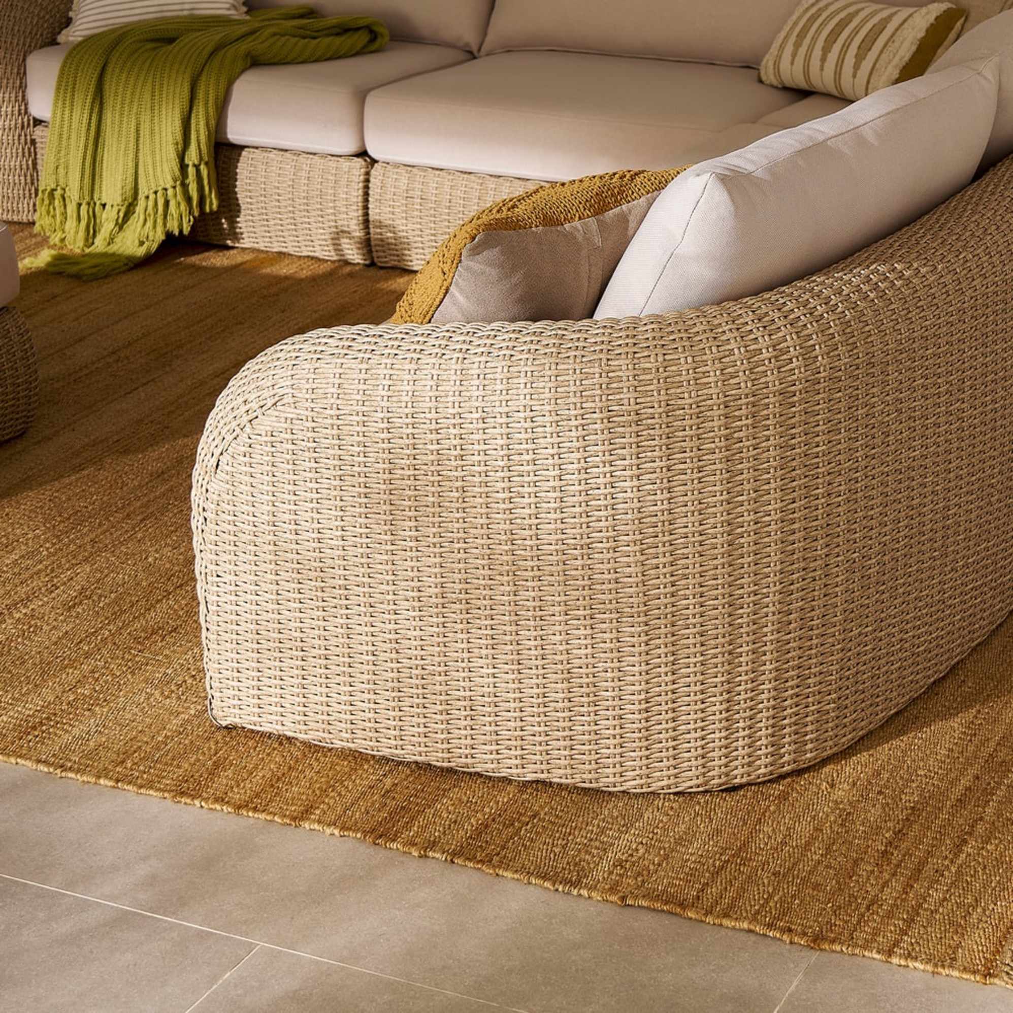 A wicker outdoor sectional sofa placed on an indoor deck.