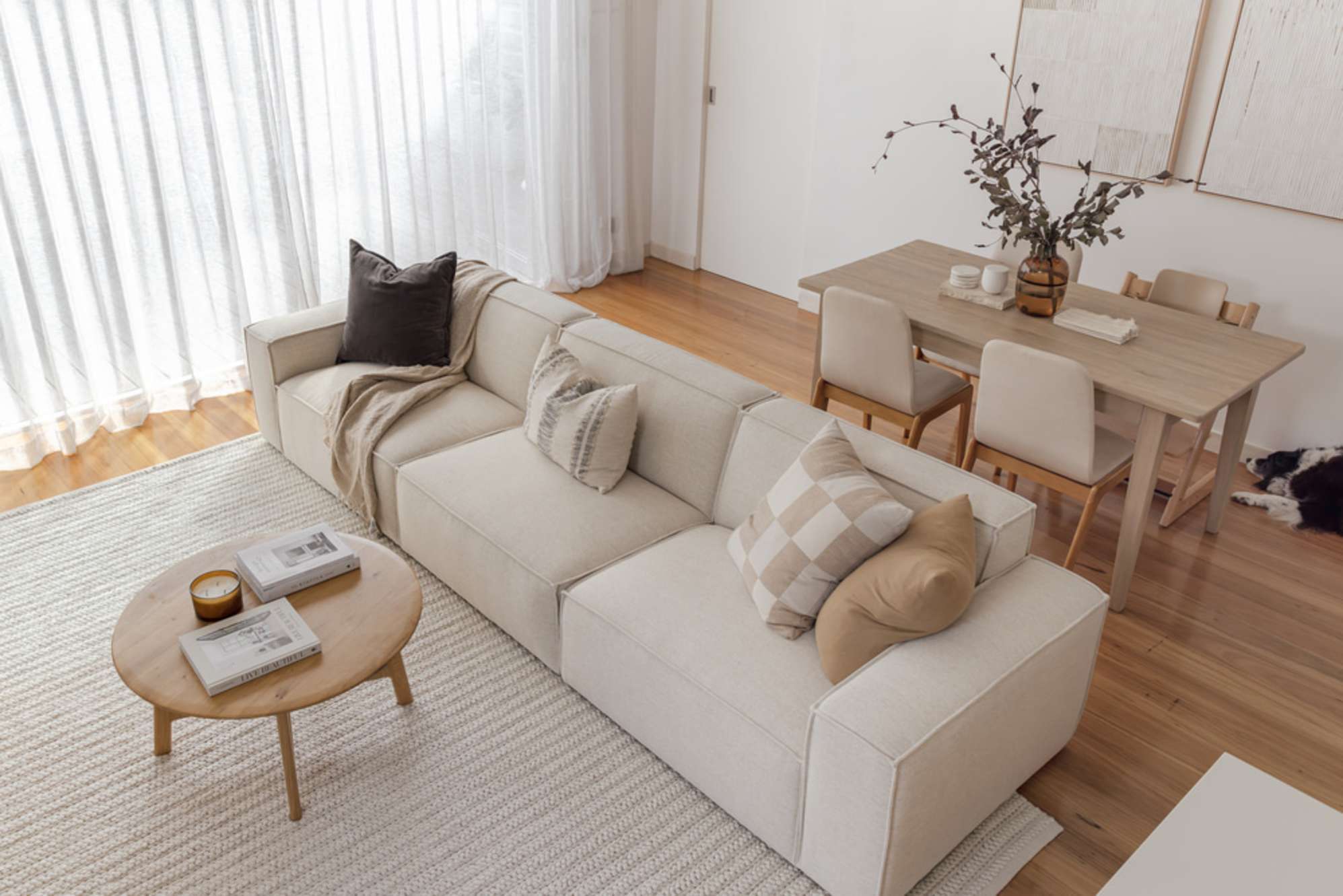 A extended sofa with a round wood coffee table.