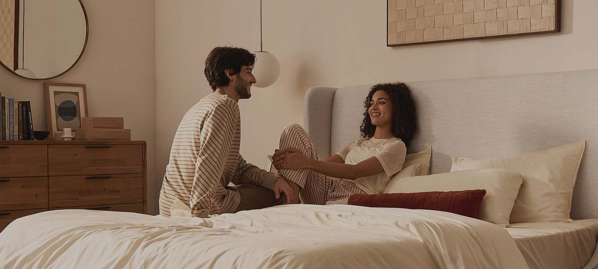 Two people sitting on a bed with a wingback headboard.