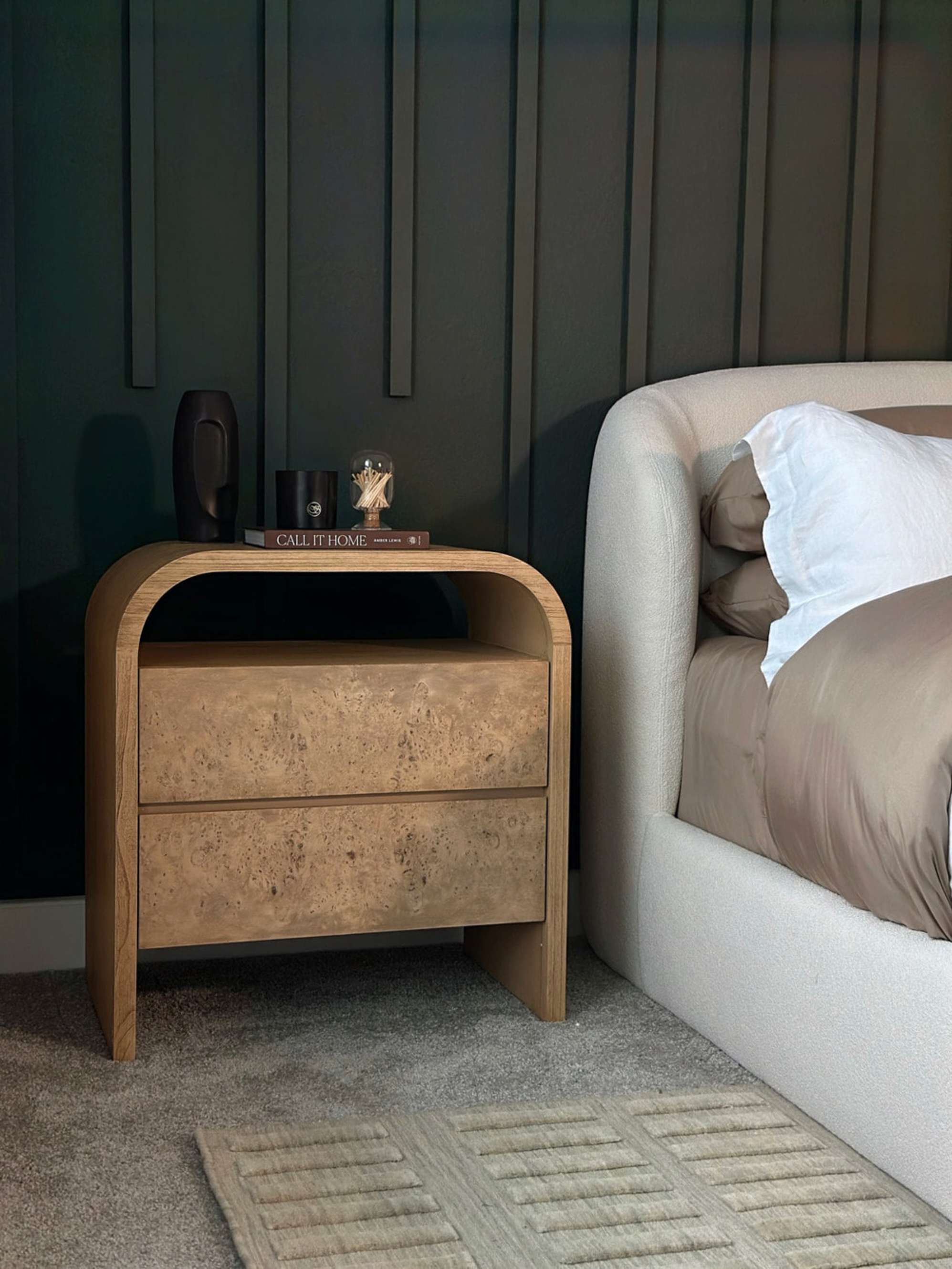 A wooden two-drawer nightstand placed next to a bed.