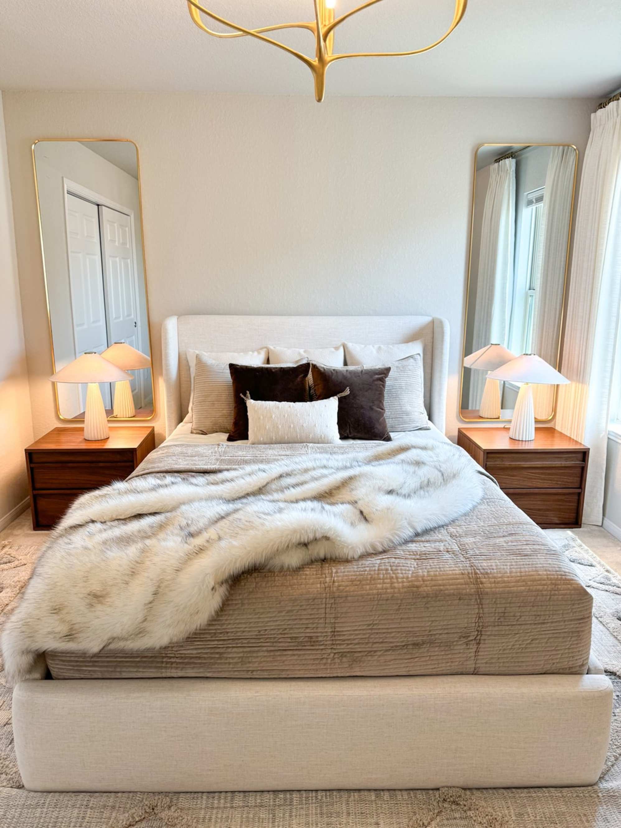 Two matching bedside tables and table lamps placed beside a bed with a wingback headboard.