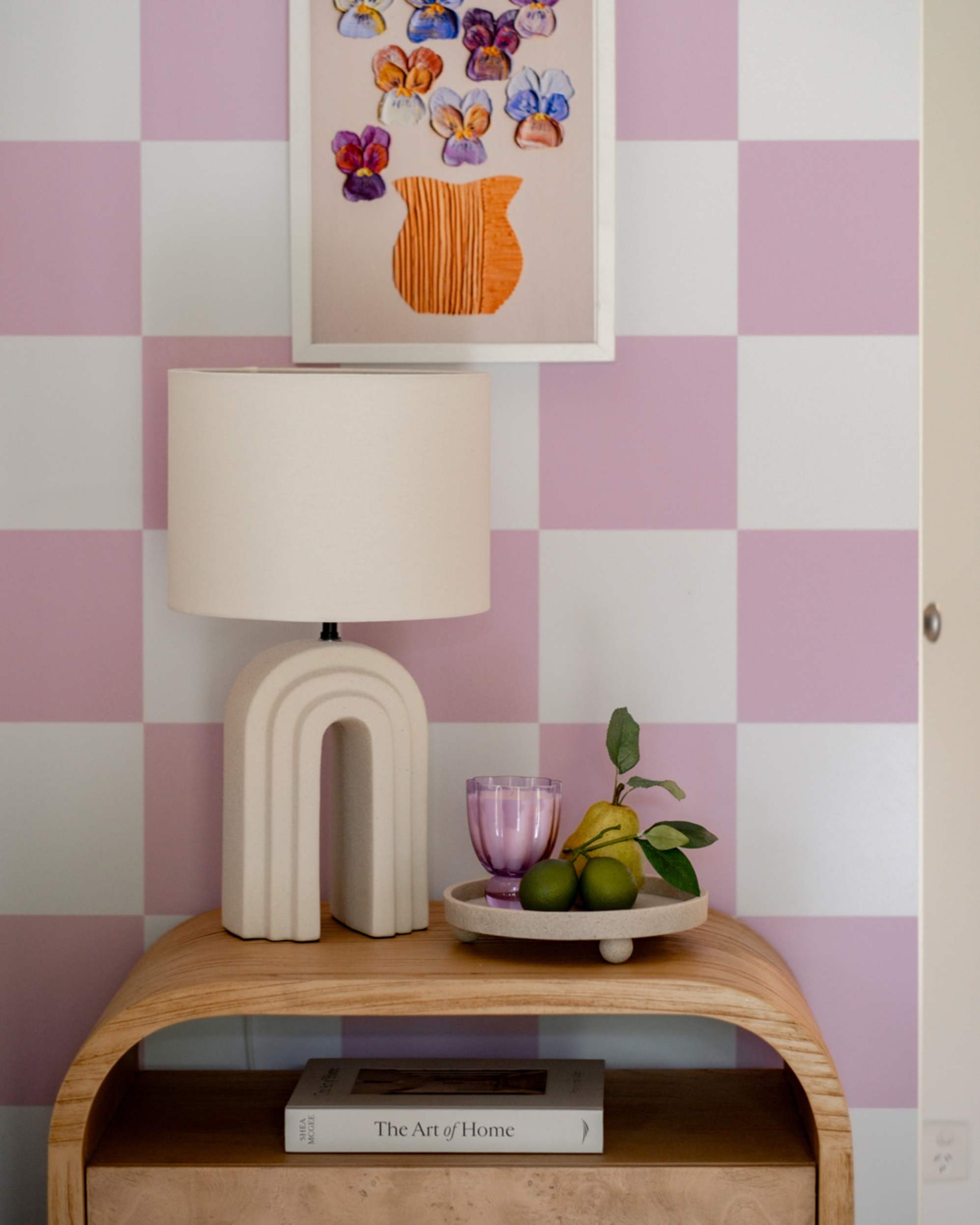 An arched table lamp placed on a bedside table with decor.