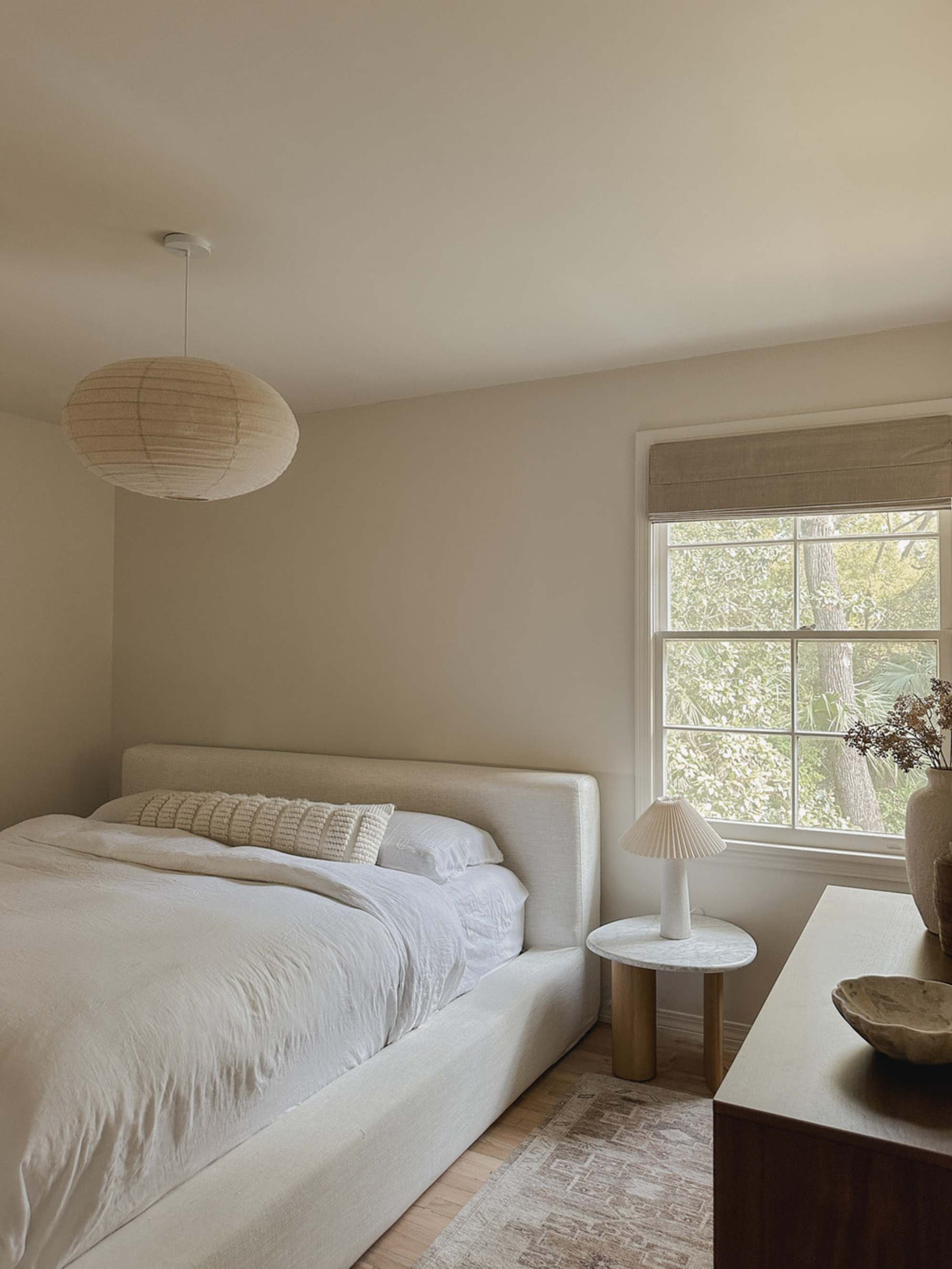 A marble side table with a table lamp placed beside a bed.