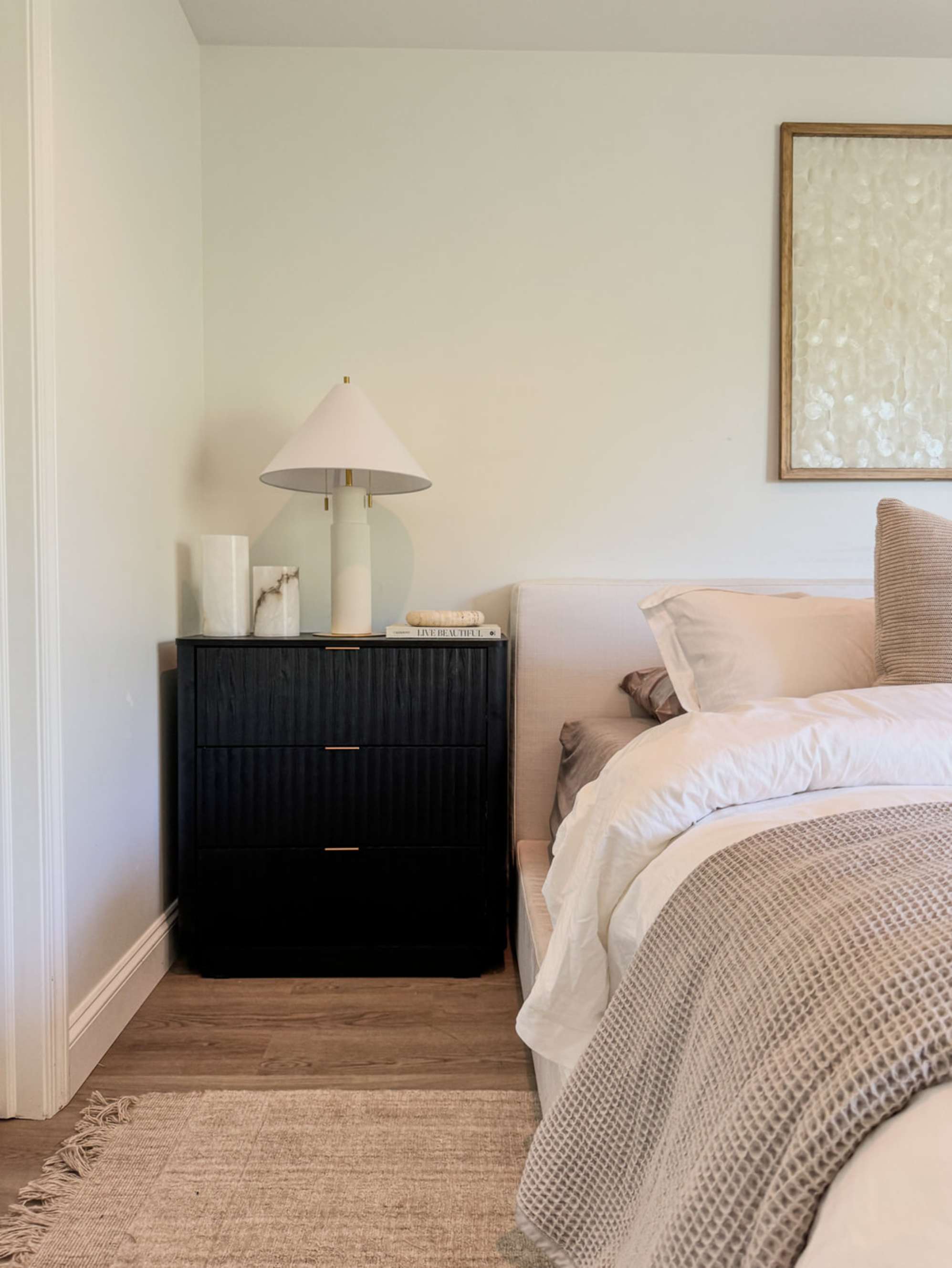 A dark wood 3-drawer nightstand with a table lamp.