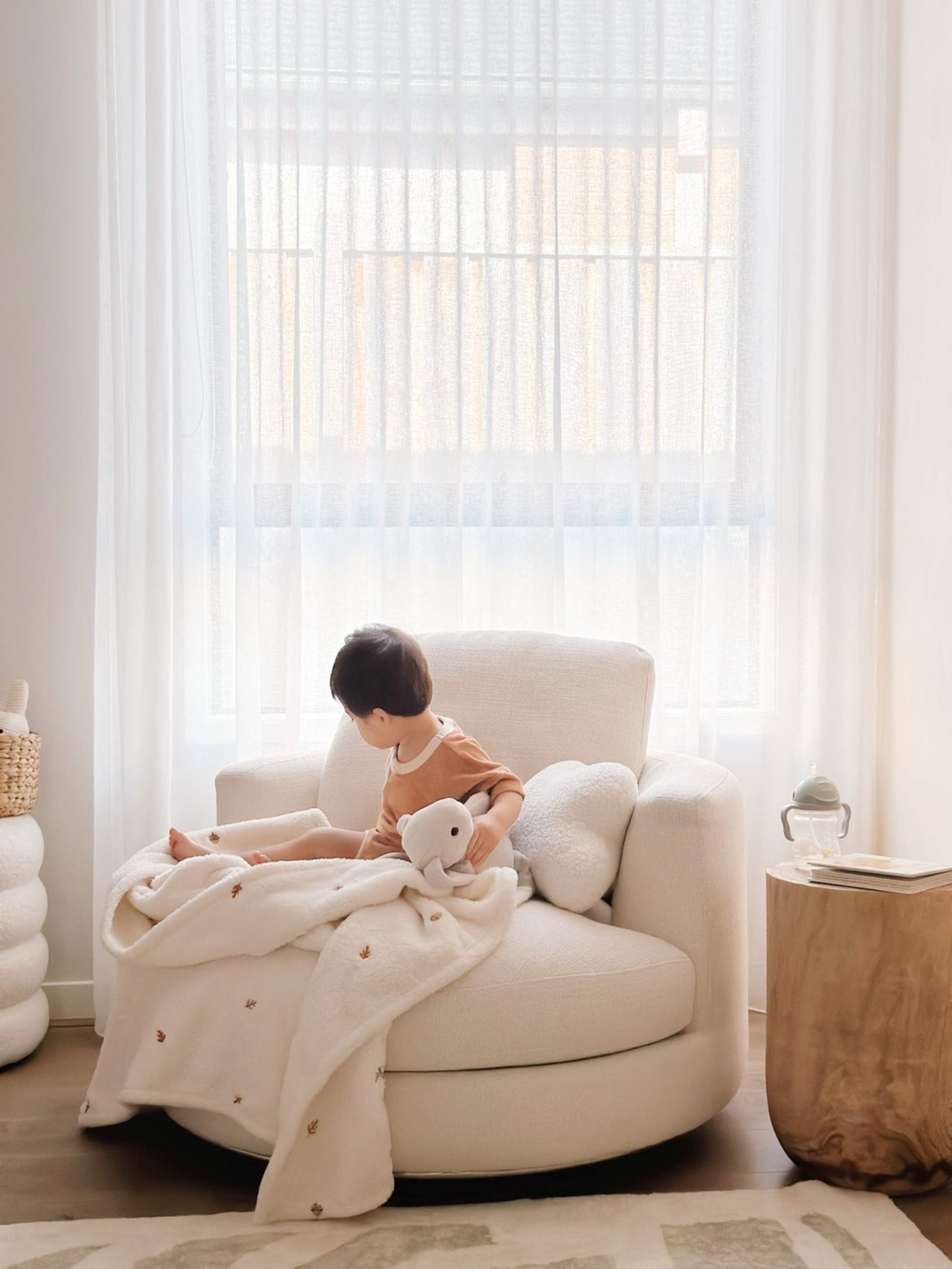 A toddler sitting on a curved 1.5 seater armchair.