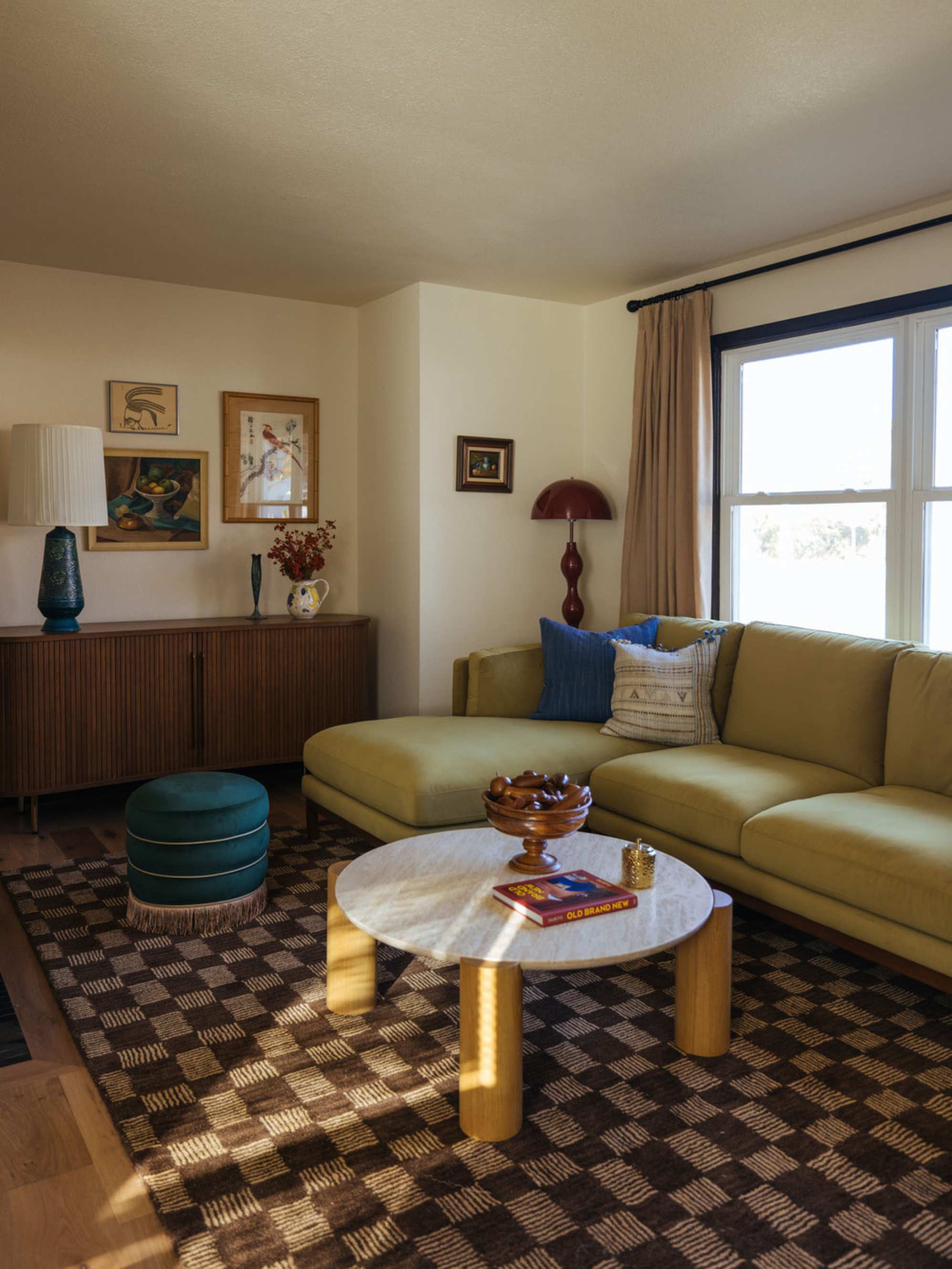 A marble coffee table is placed in a living room with a velvet sectional sofa.