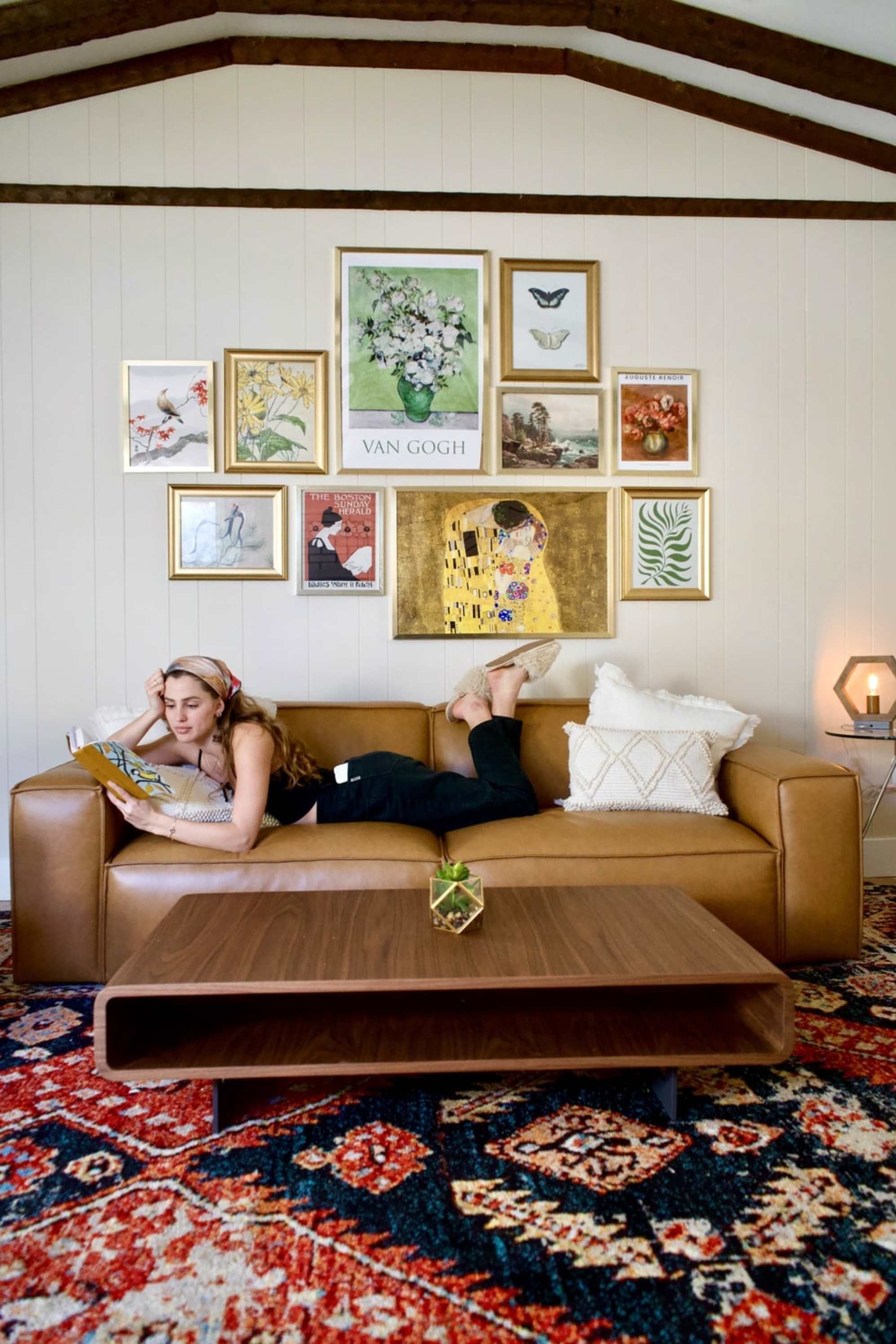 A person lying down on a leather sofa while reading a book.