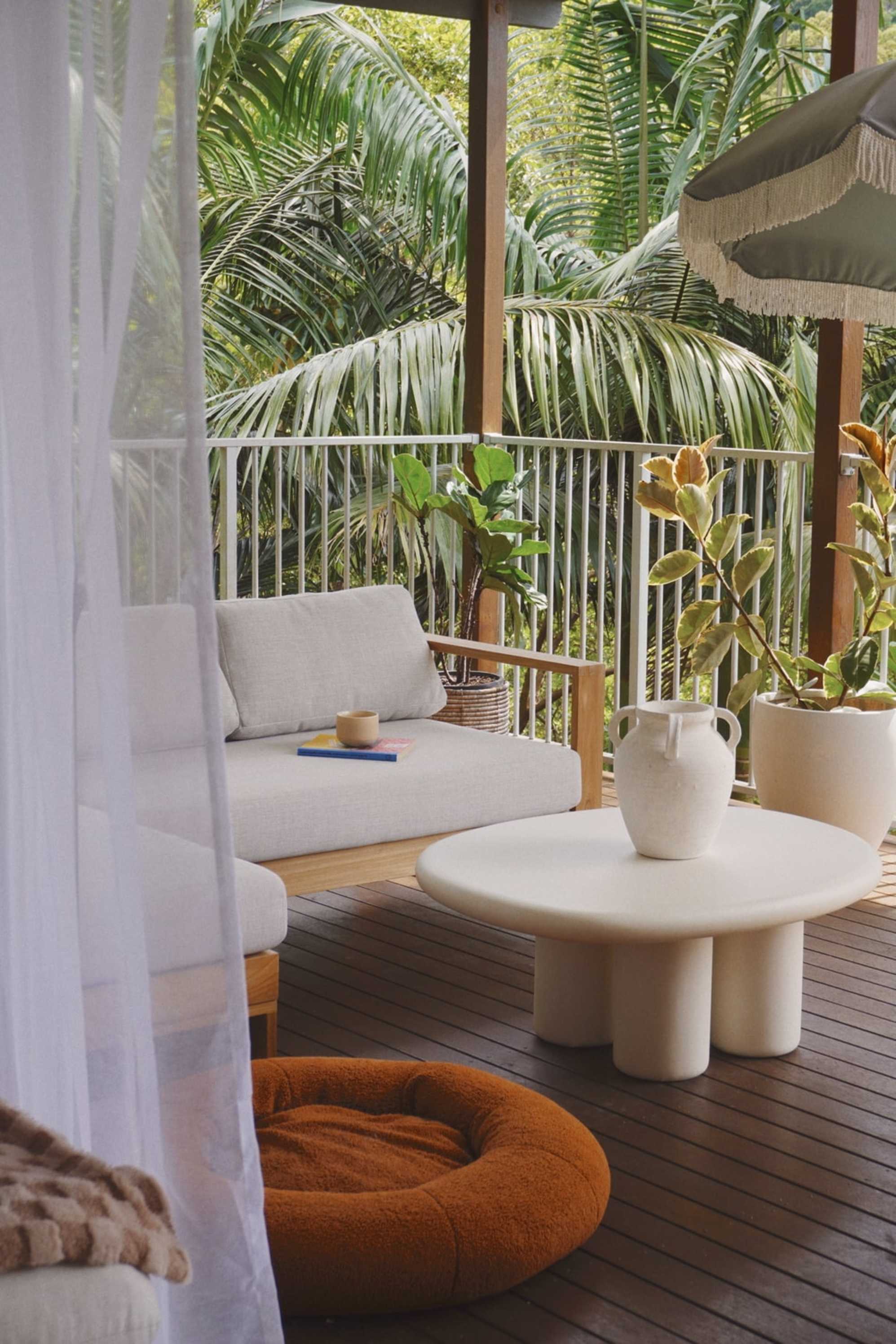 A coffee table placed out on a deck with a teak chaise sectional sofa.