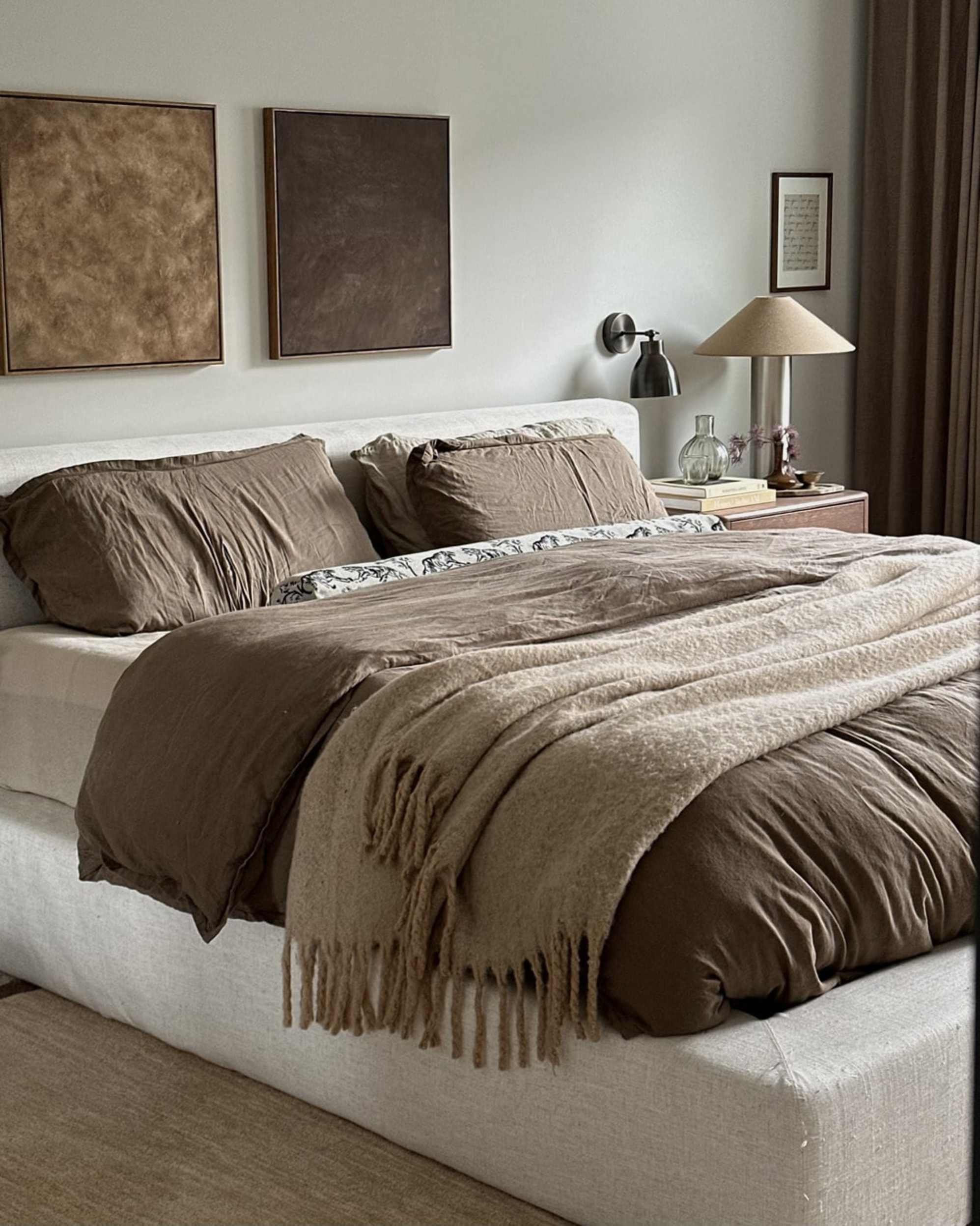 A platform bed with brown bedding and cushions.