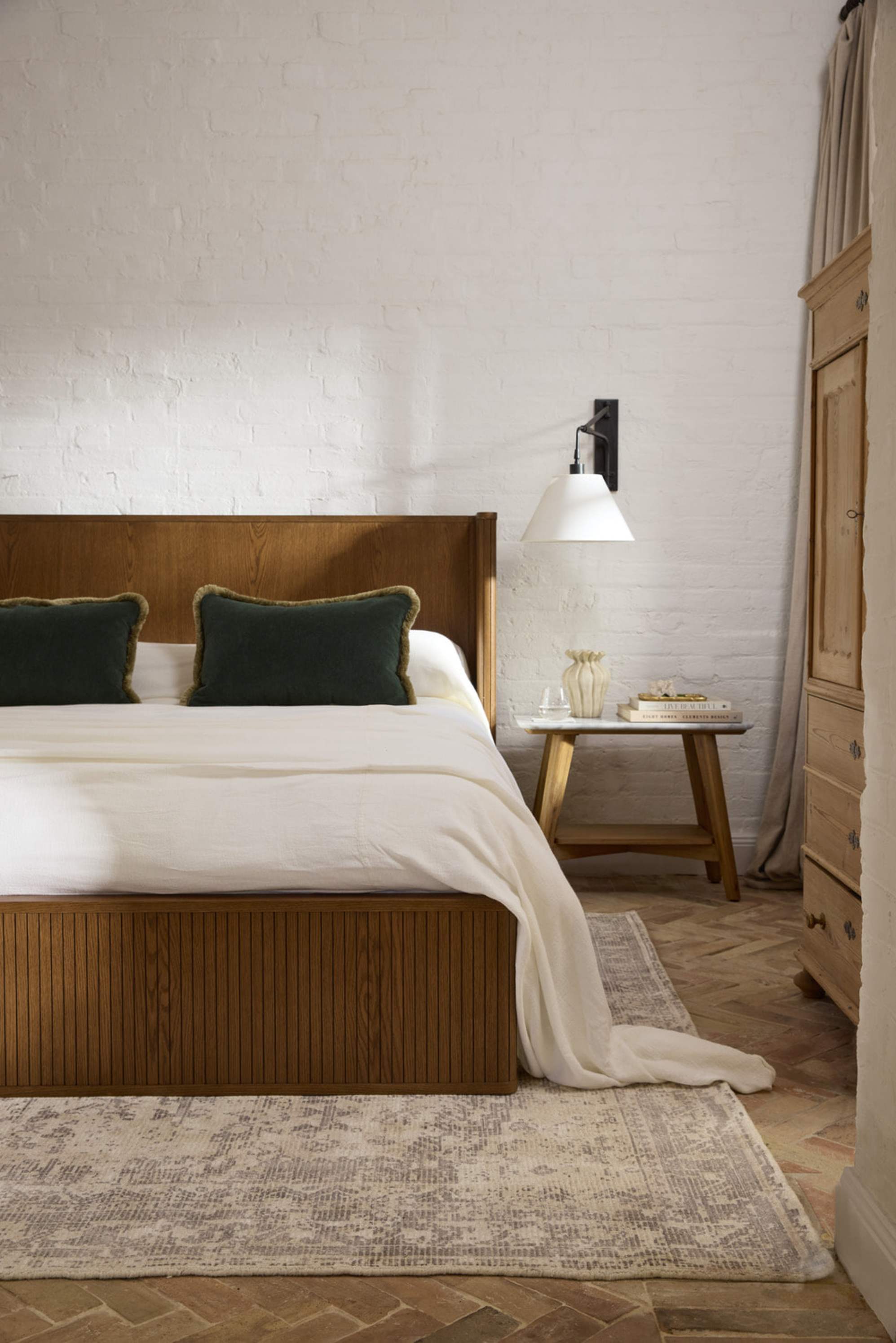 A wooden bed and a marble side table in a bedroom.