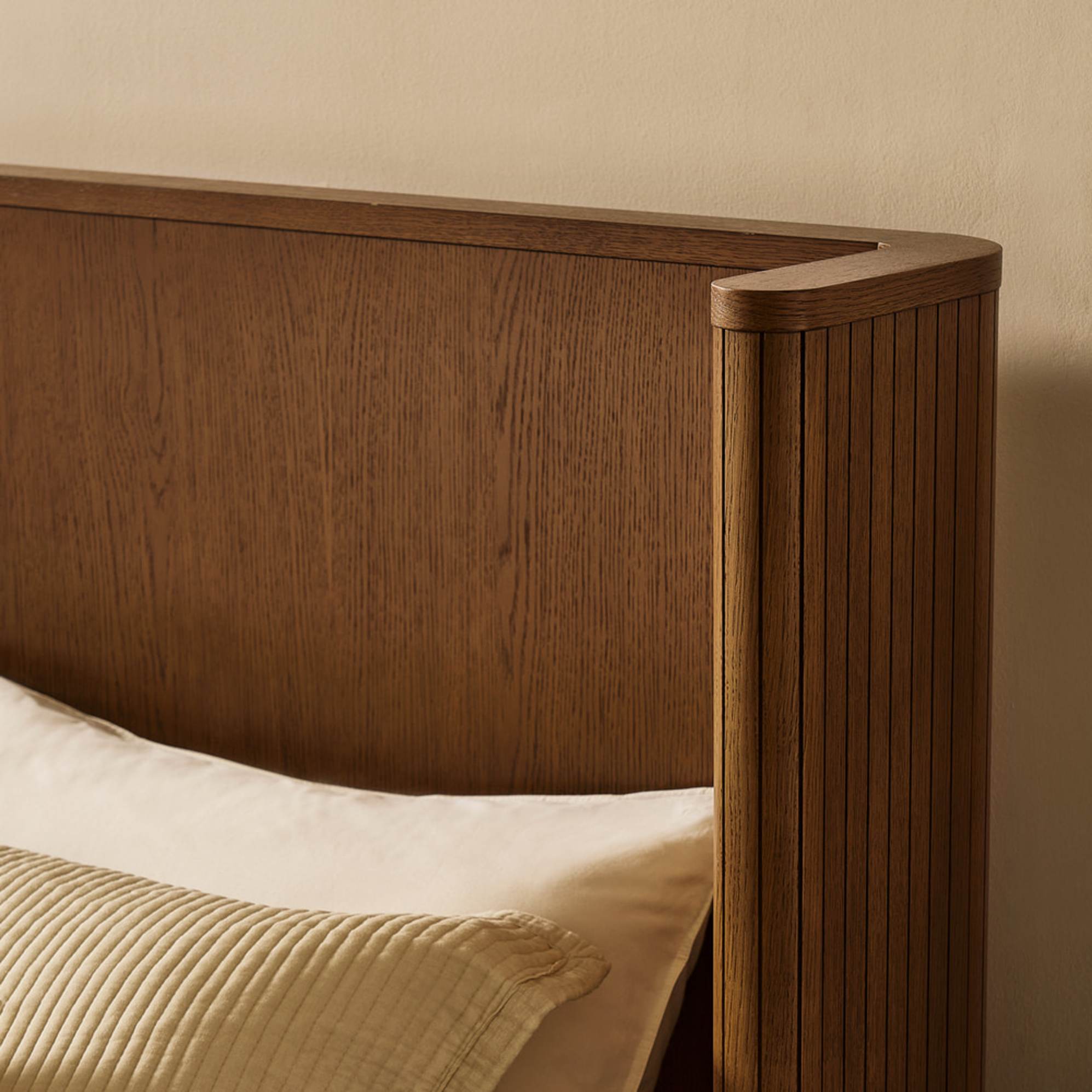 A wooden bed with a wingback headboard.