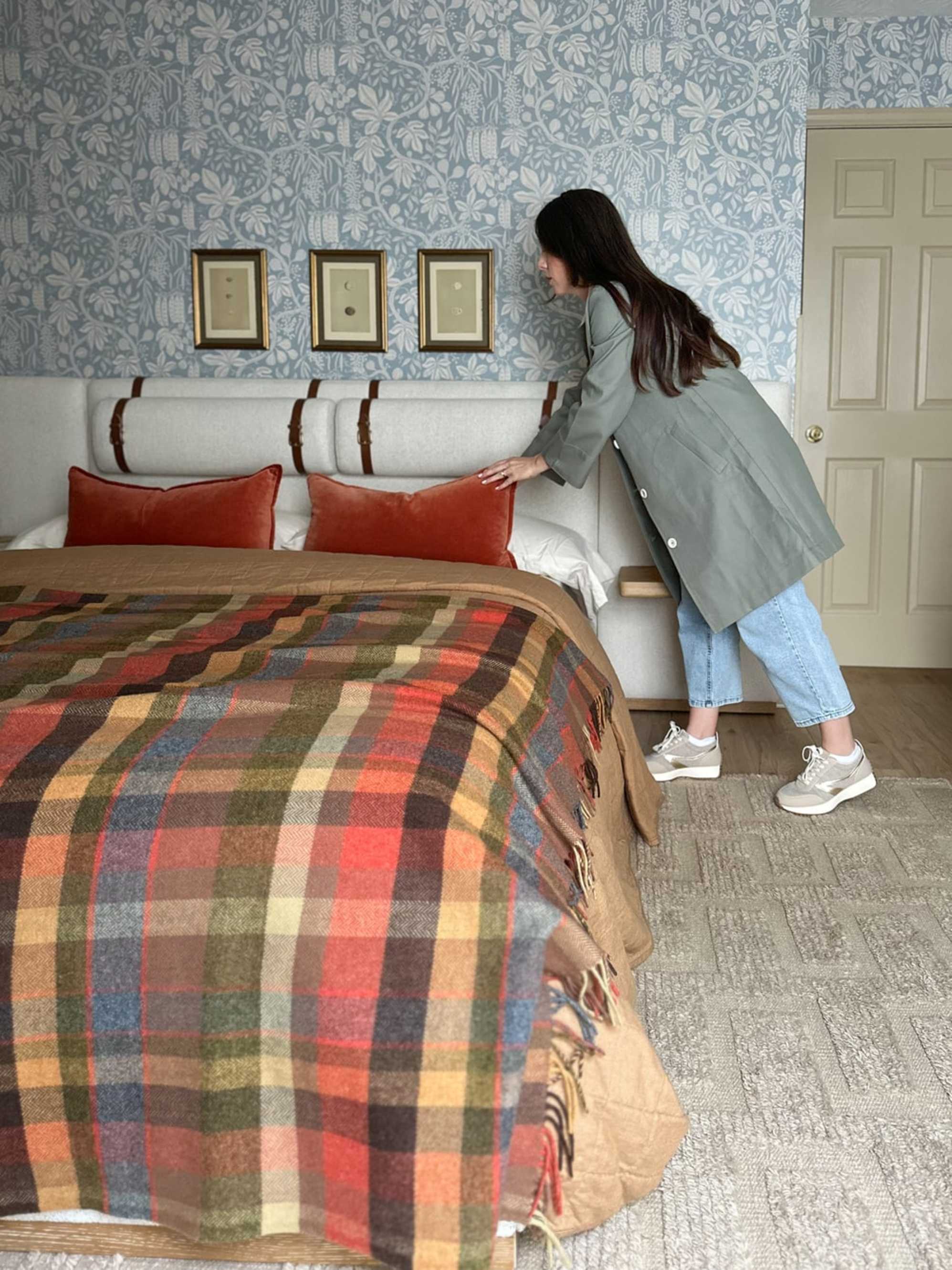 A person arranging cushions on a bed.