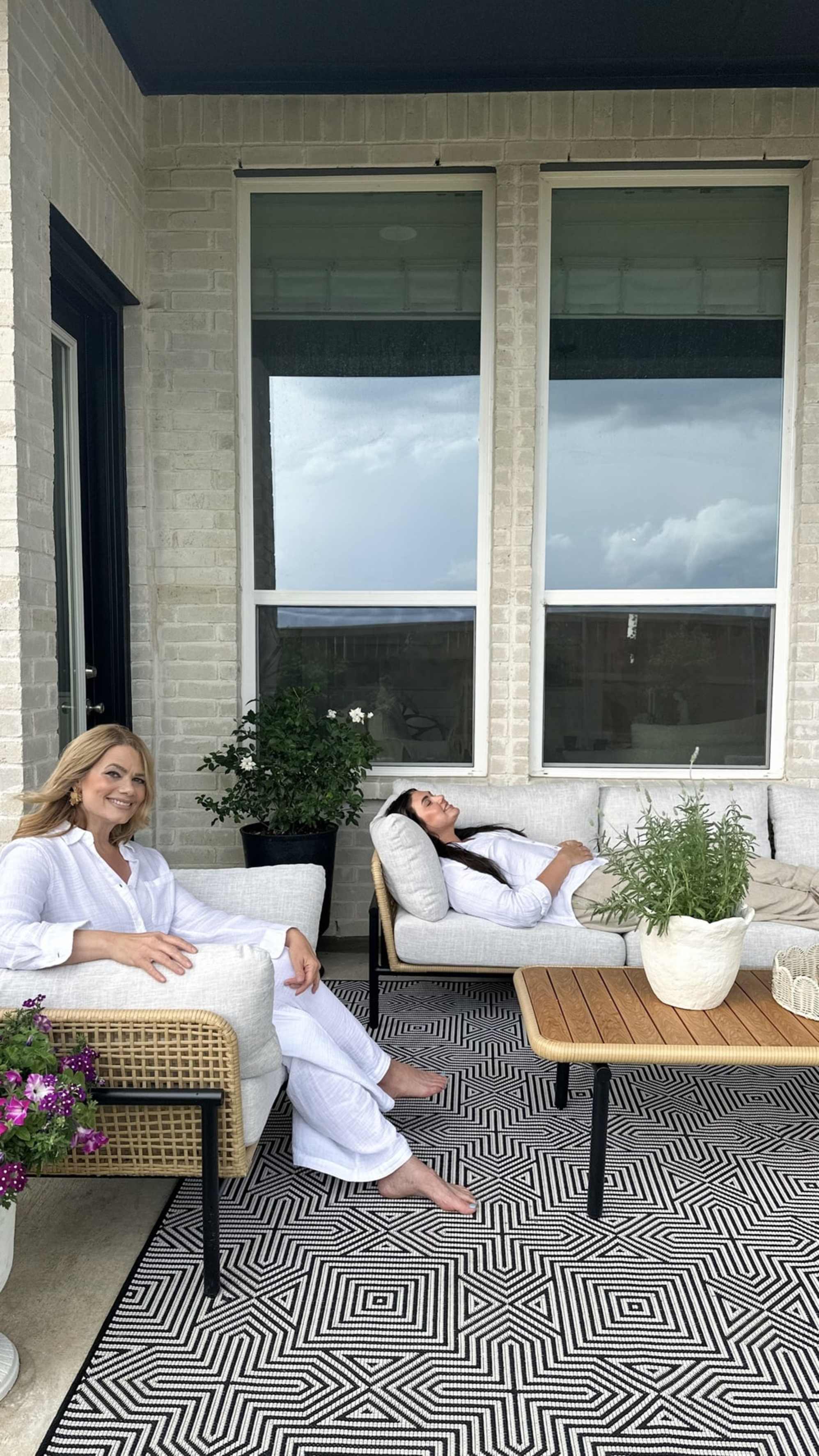 Two people lounging on an outdoor sofa and lounge chair.