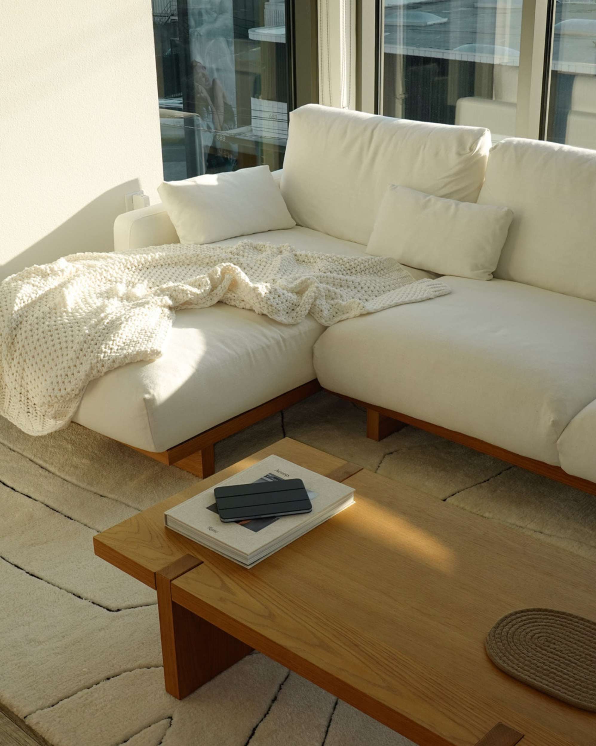 A modular sofa with a matching wooden coffee table placed atop an area rug.