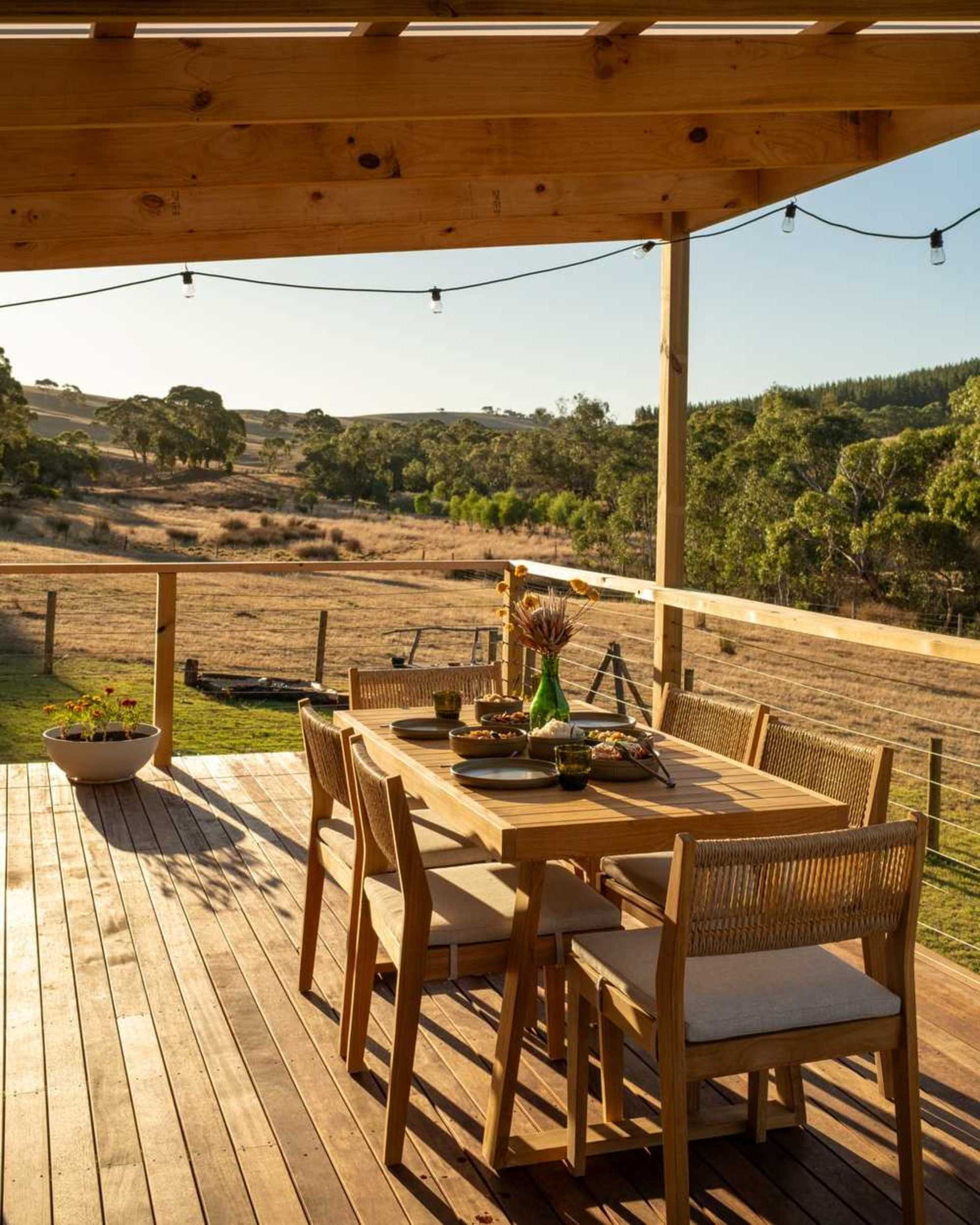 A teak outdoor dining set placed on a wooden deck.