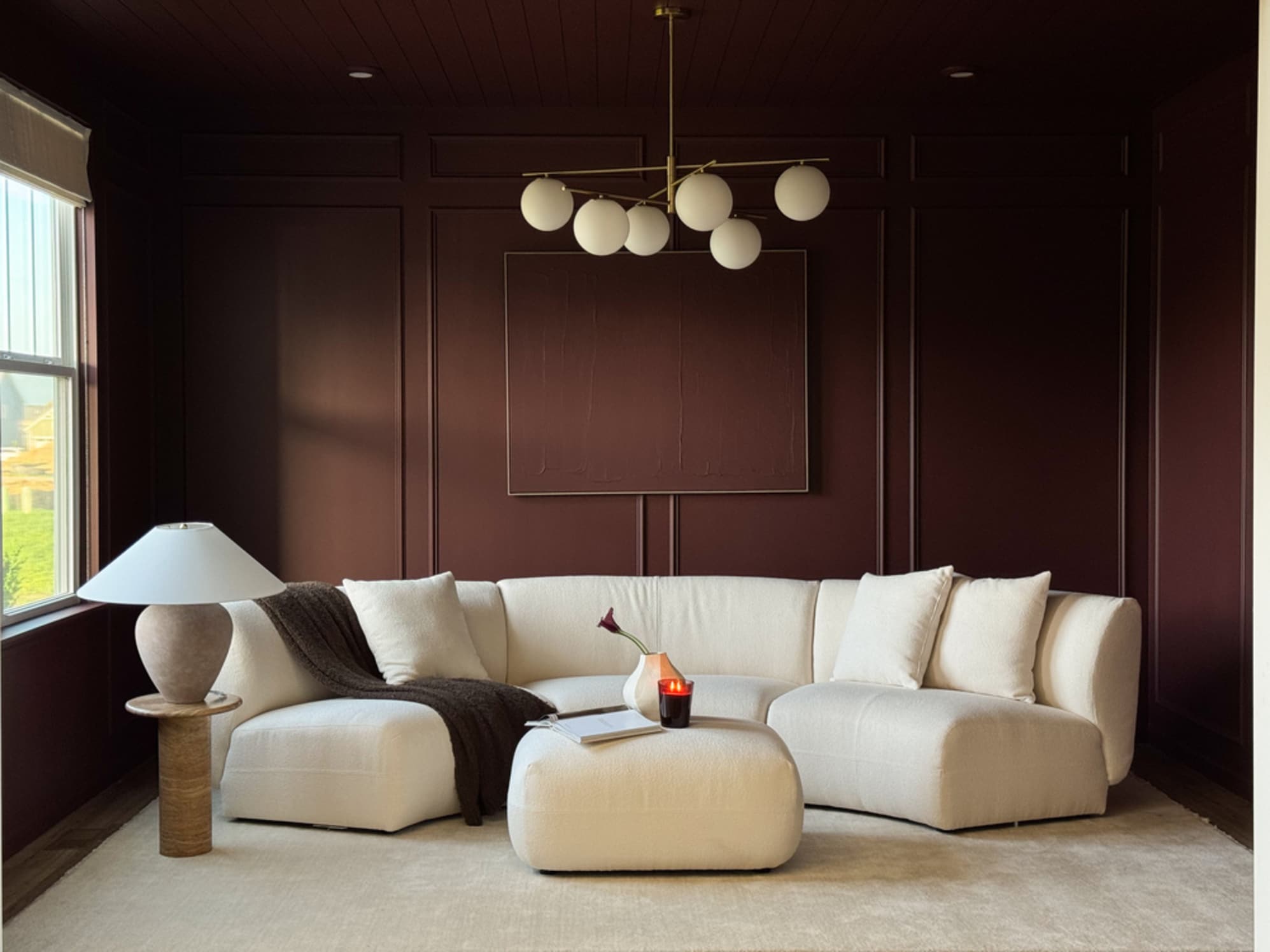 A curved performance boucle sofa placed in a lounge with a chandelier hanging atop.