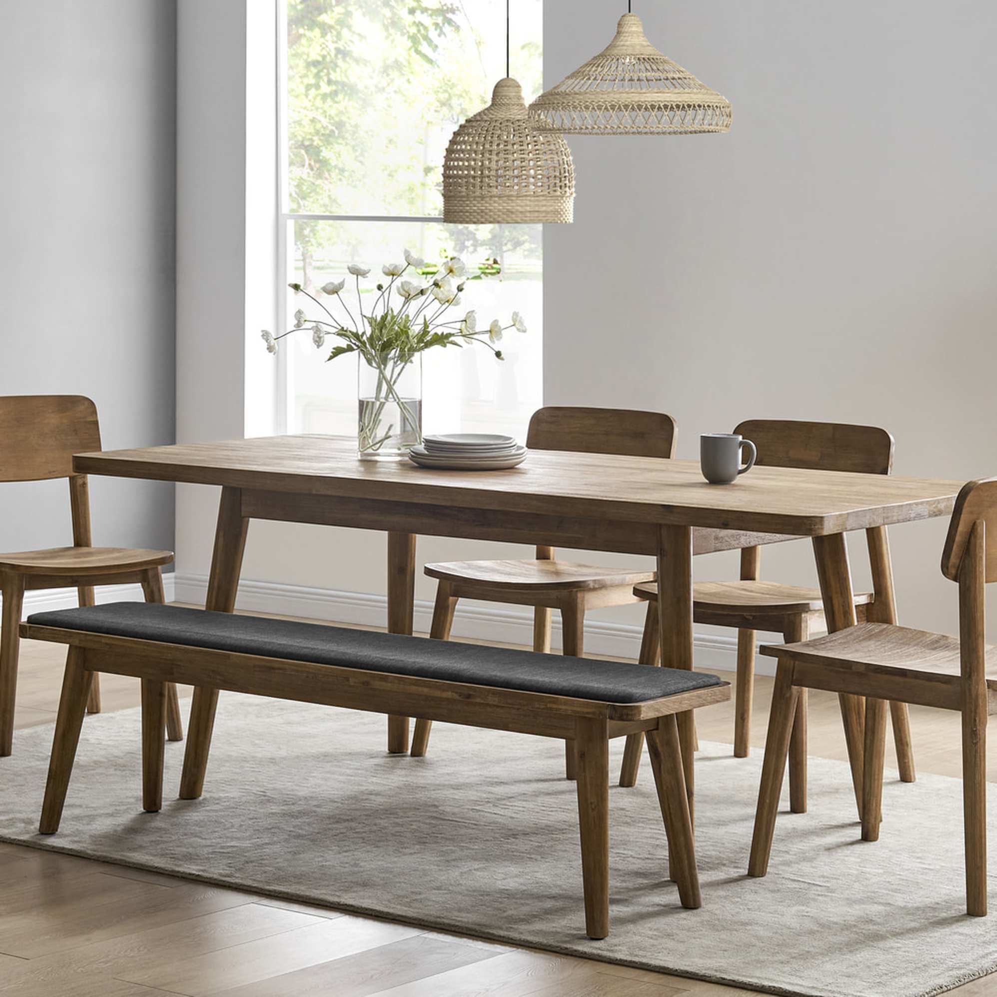 An acacia wood extendable dining table set with matching chairs and a bench.