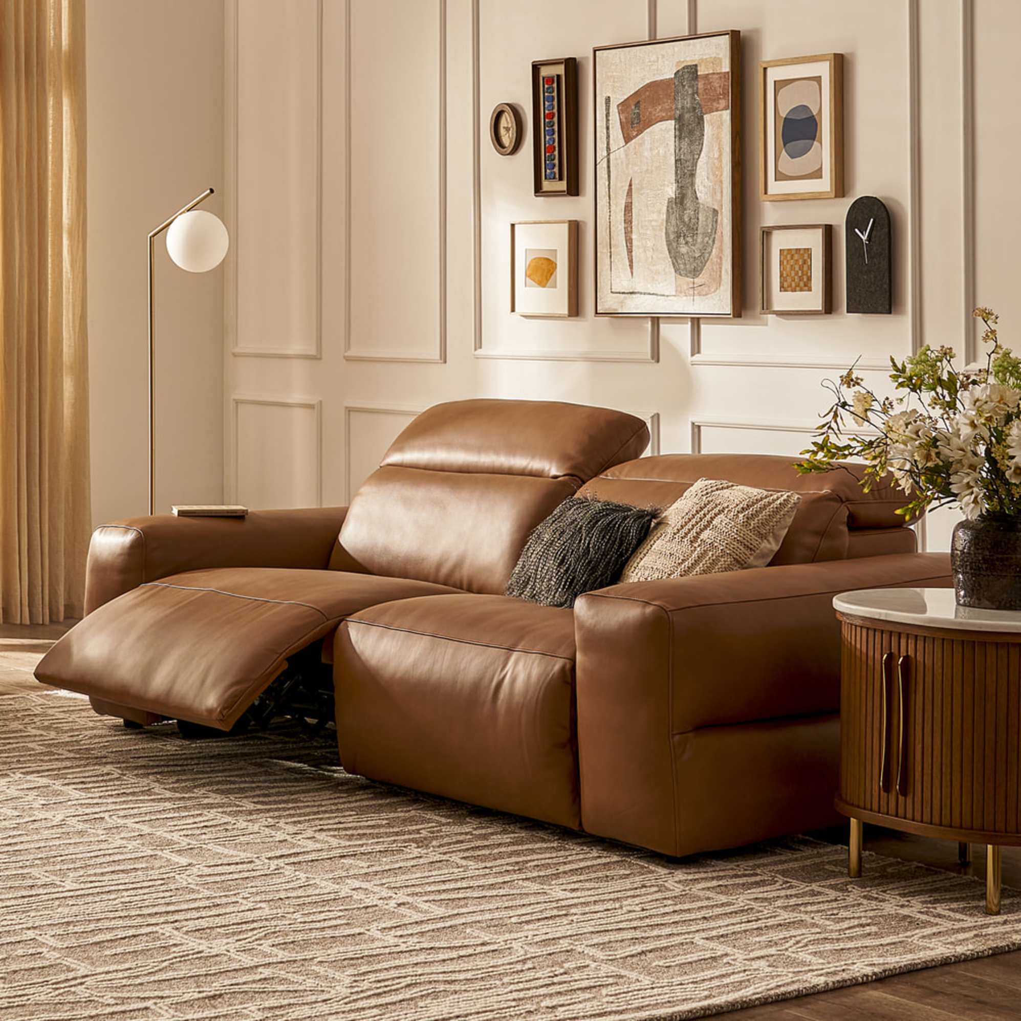 A leather recliner sofa placed in a living room atop an area rug.