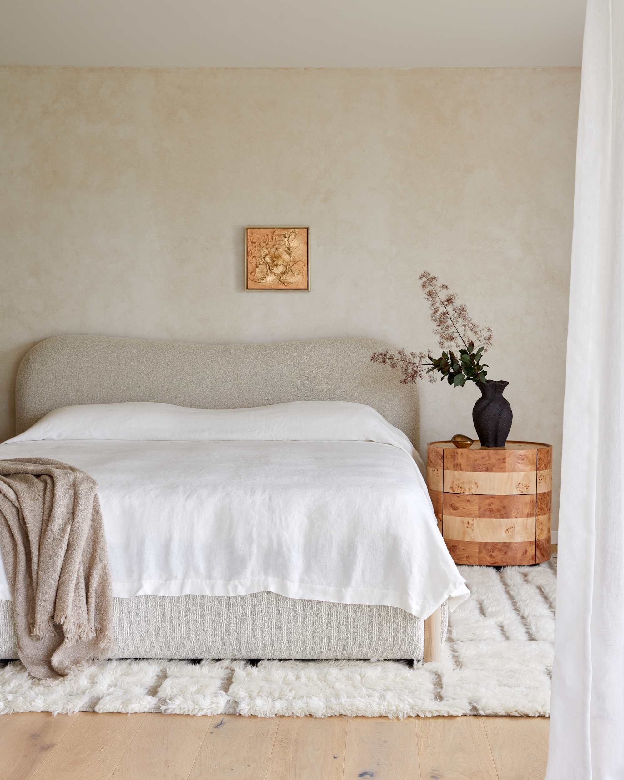 A performance bouclé bed with a curved headboard.