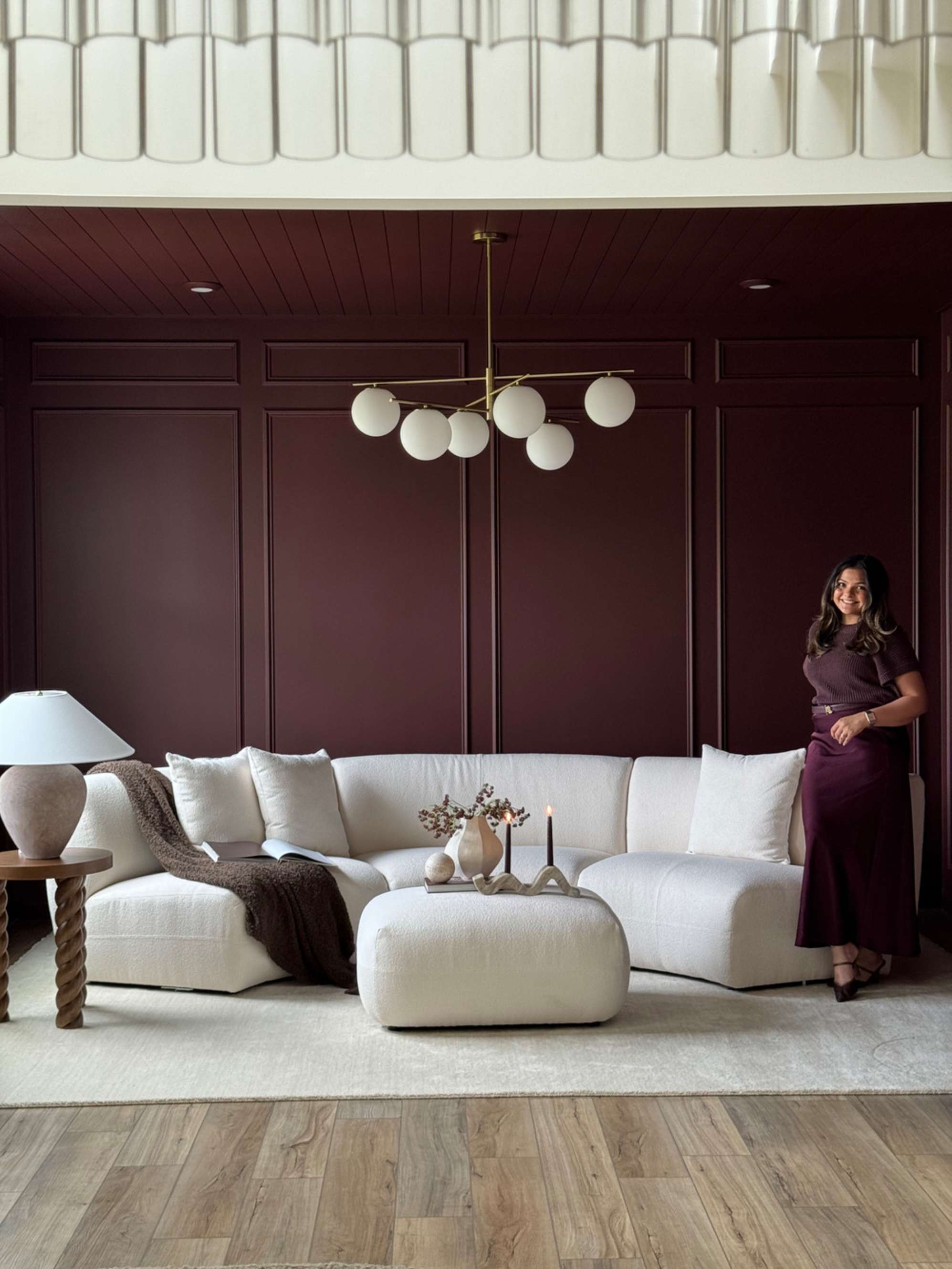 A person standing beside a performance fabric curved sofa in a lounge.