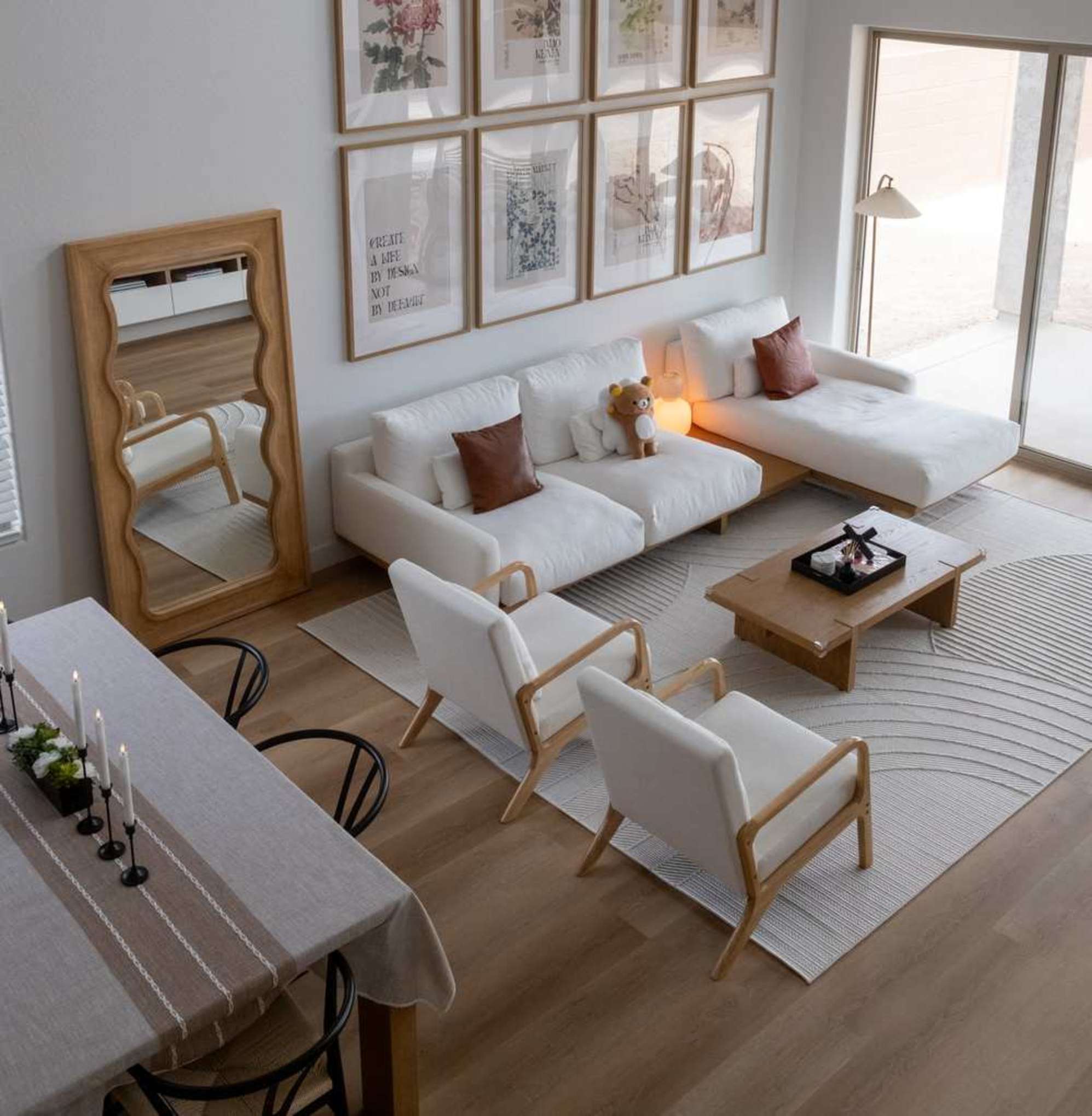 A sectional sofa, floor mirror, and two armchairs placed in a living room with a large gallery wall.