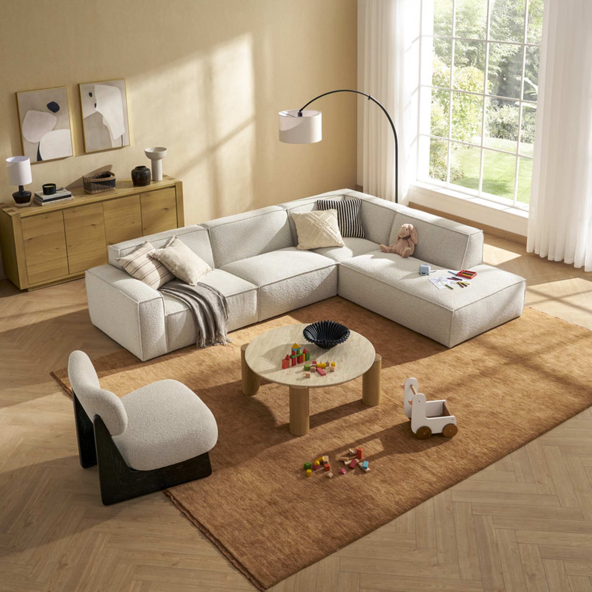 An extended side chaise sectional sofa in a living room with children toys and markers strewn on it.