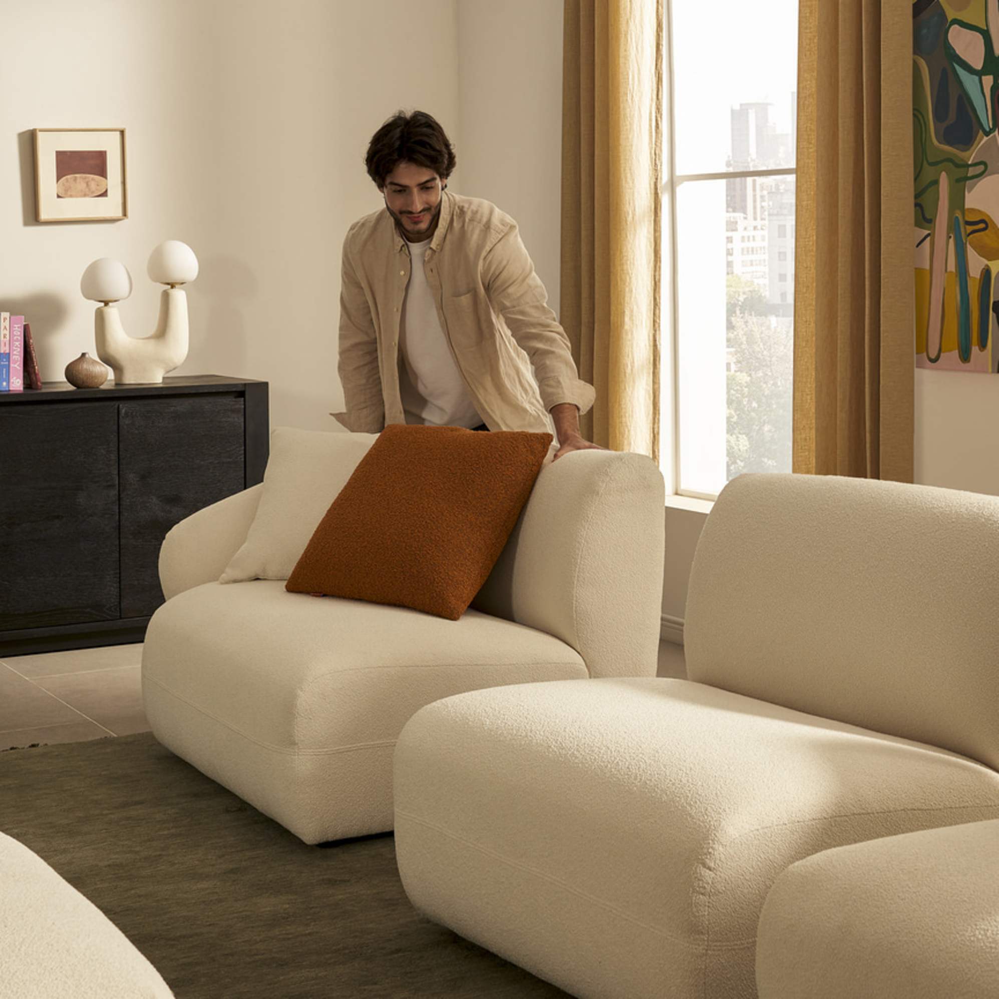 A person arranging a modular sofa unit in a living room.