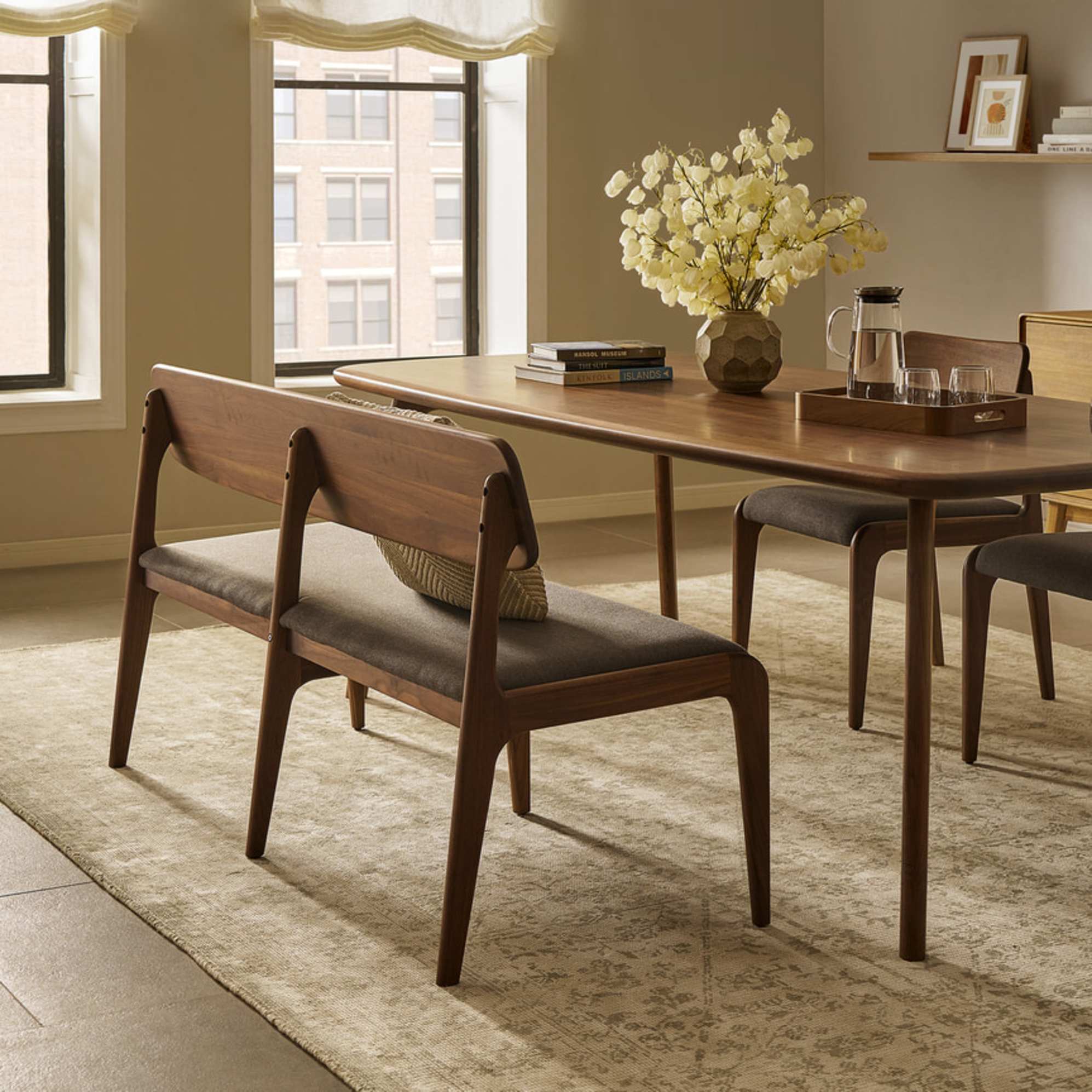 A walnut wood dining table and matching walnut wood dining bench. 