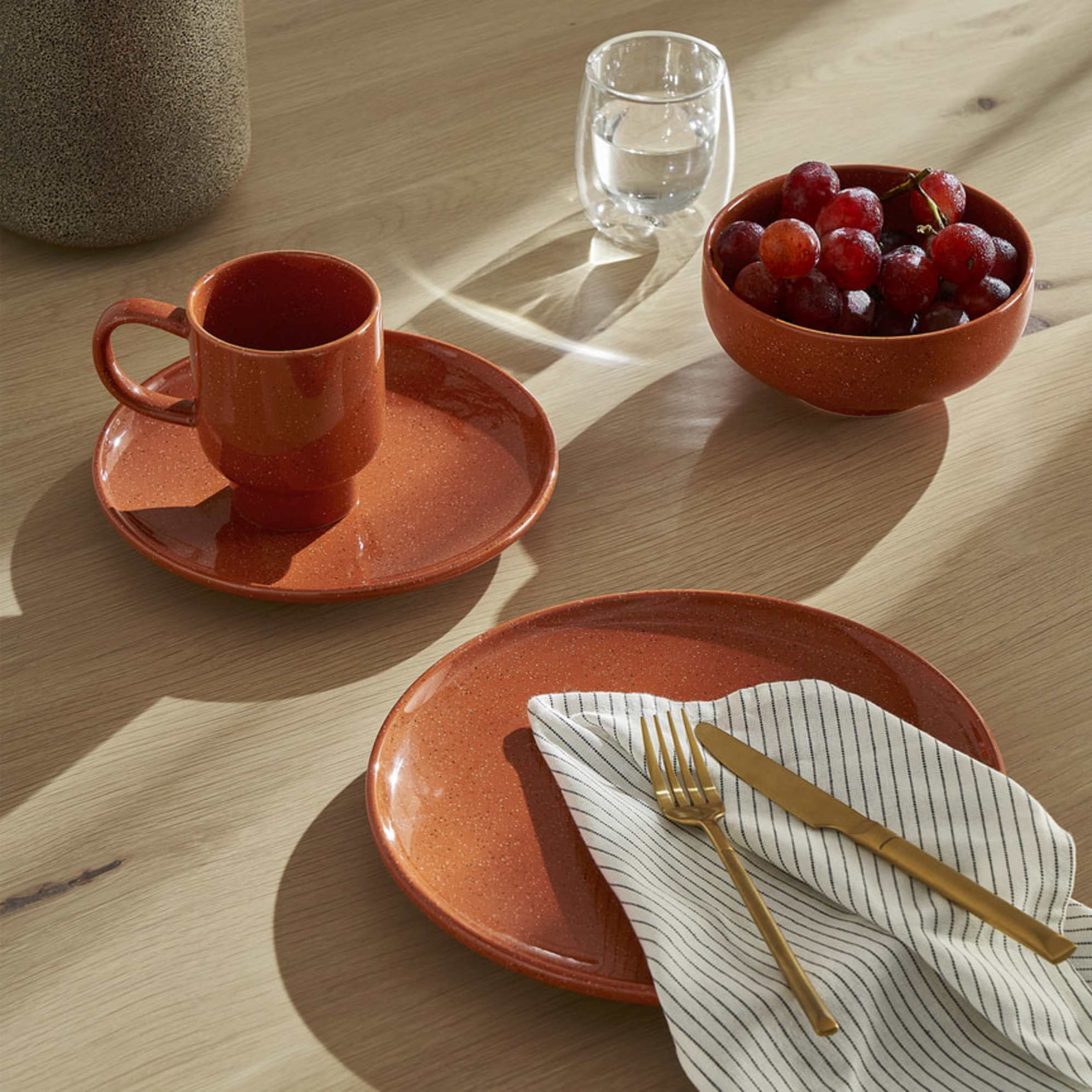 Two red dinnerplates and a cup placed on a dining table.