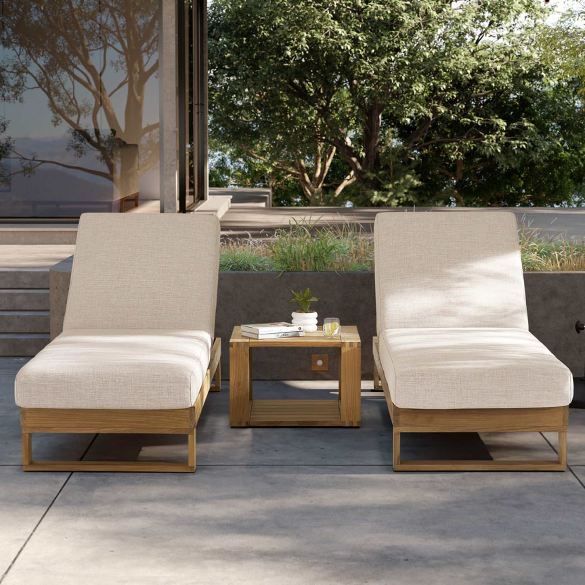 Two matching teak outdoor chaise lounges with a teak box side table placed in-between.